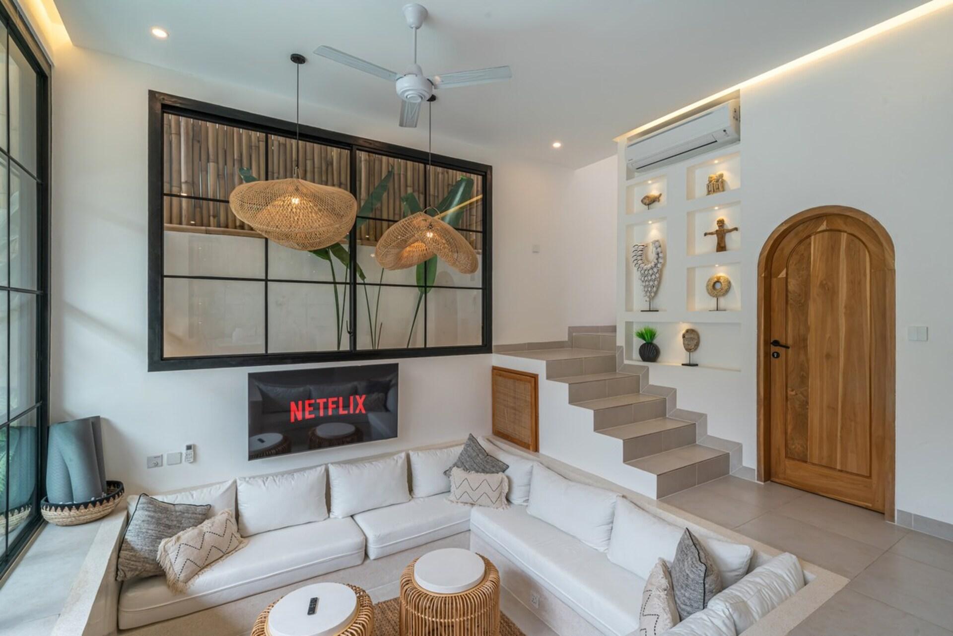 Sunken white lounge at Villa Polanco, rattan drum tables and stairs beyond