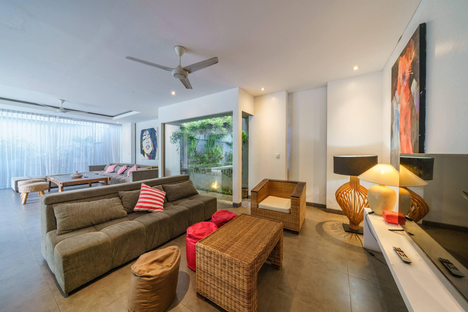 Open living floor at Villa Paloma with a deep sectional, pop-art canvas and rattan armchairs