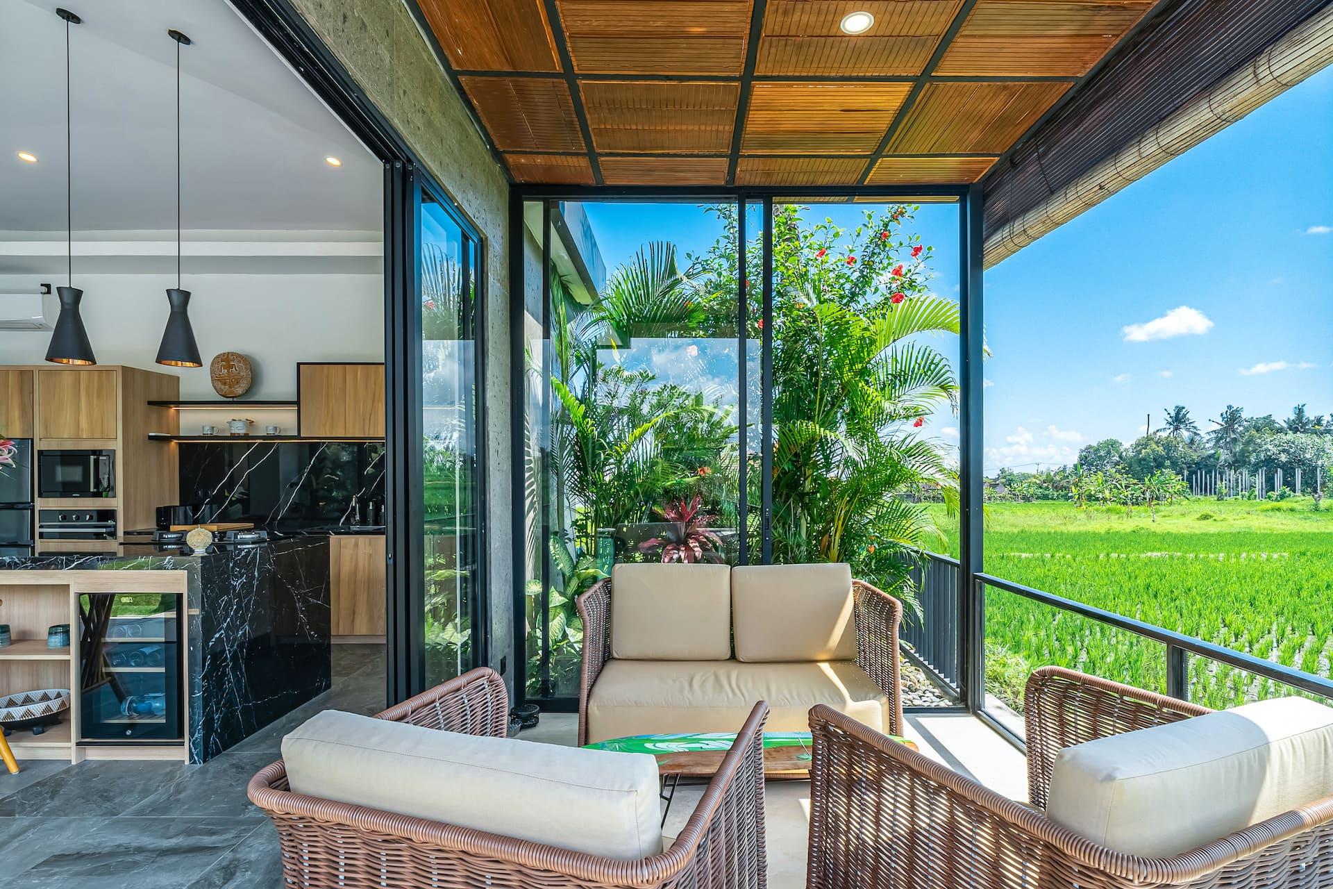 Covered rice-field pavilion at Villa Bliss with rattan sofa and armchairs behind a glass balustrade