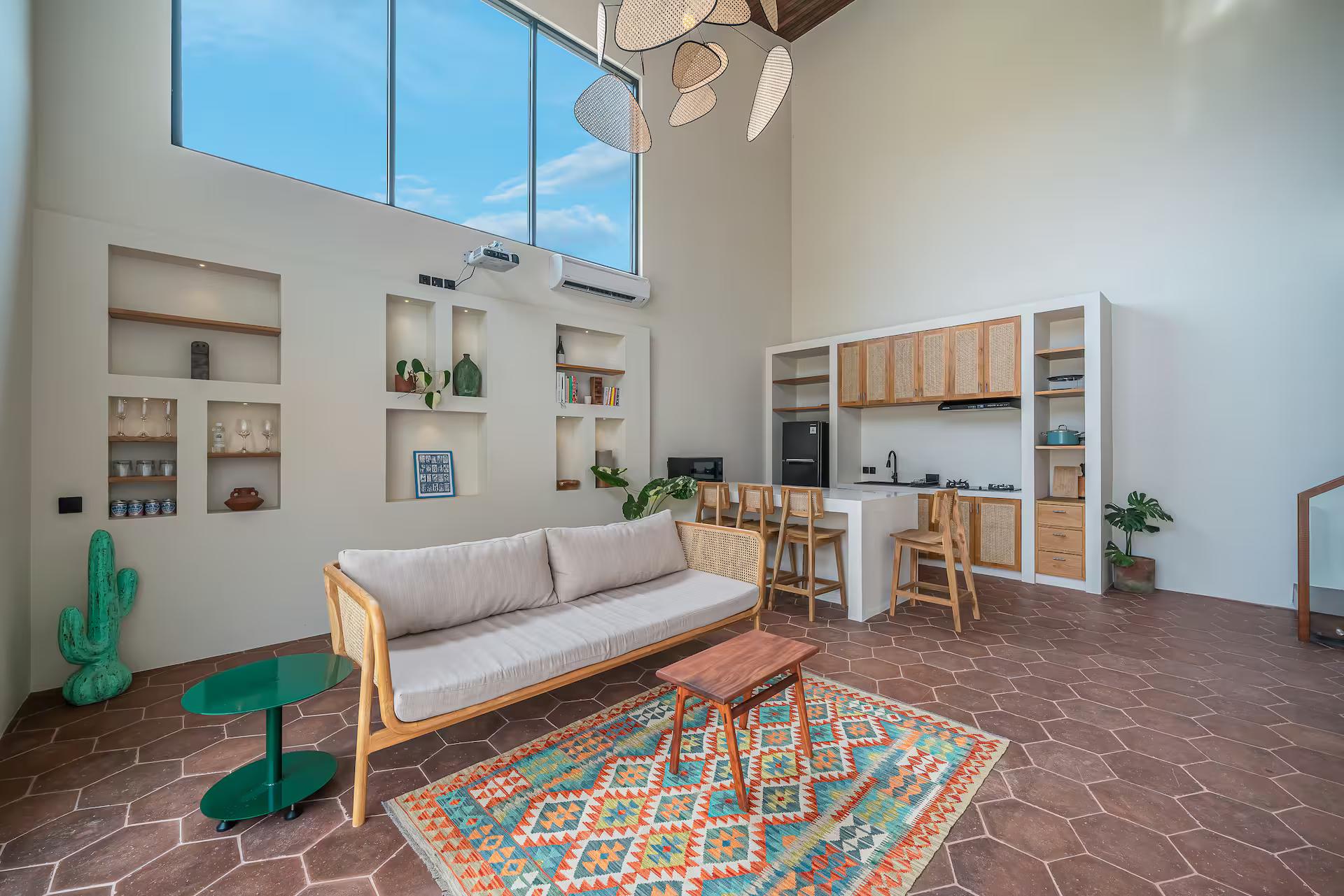 Cane sofa and kilim rug on terracotta hexagonal tile in the double-height living room