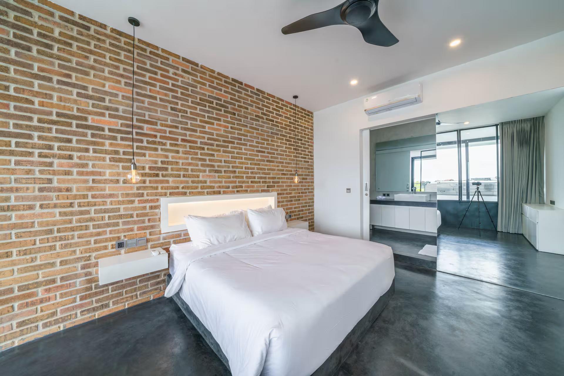Bedroom at Loft Carolyn 2 with an exposed red-brick wall and a concealed light behind the bed