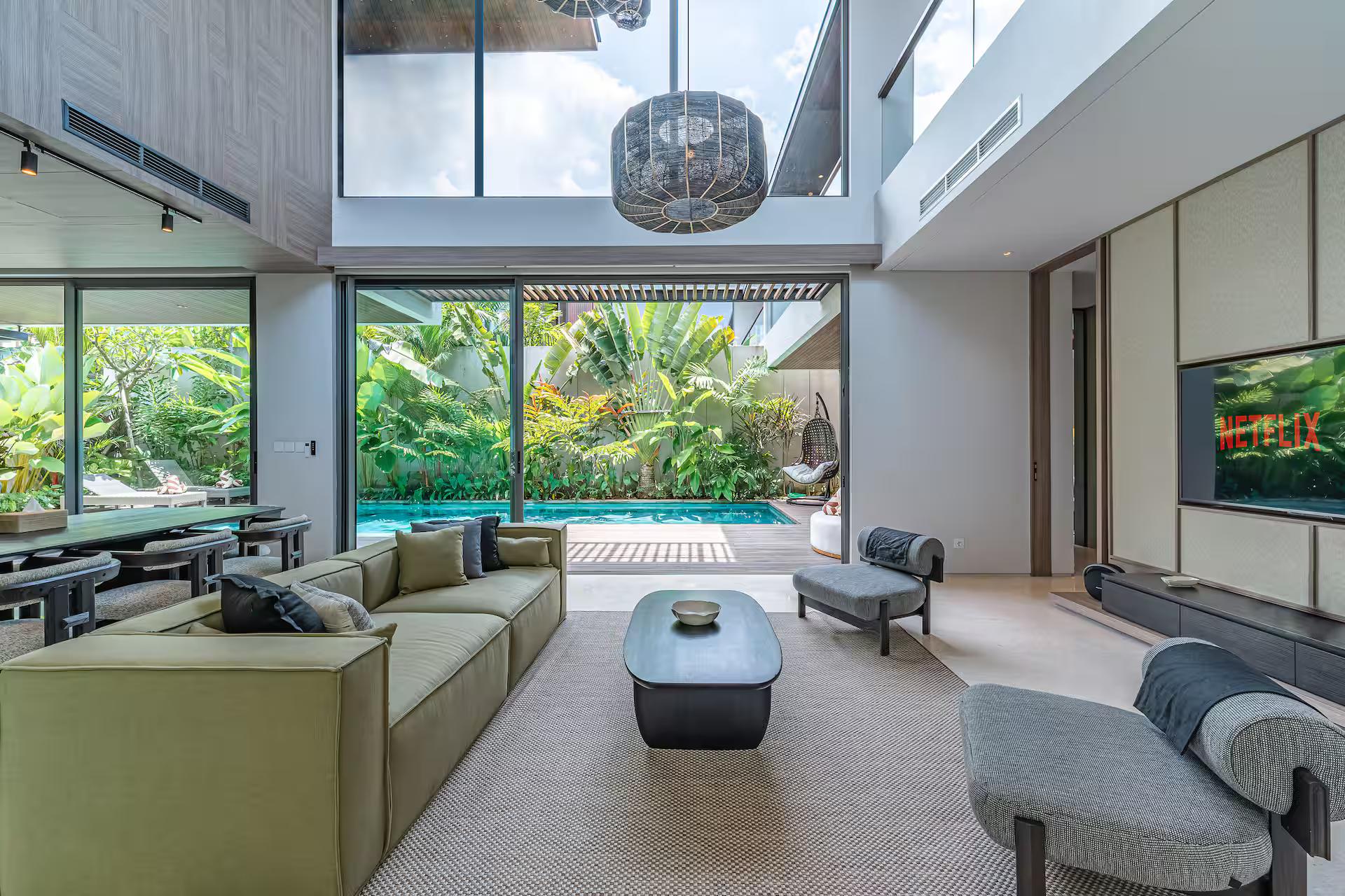 Double-height living room at Villa Akar & Daun opening to the pool through tall glass