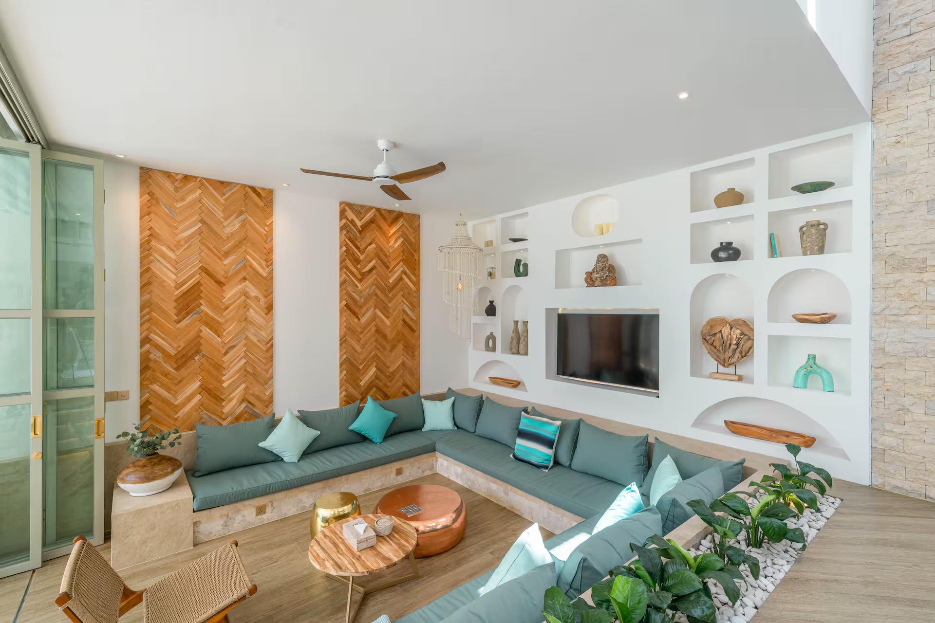 Sunken living room with sage built-in seating and a herringbone timber wall behind the television