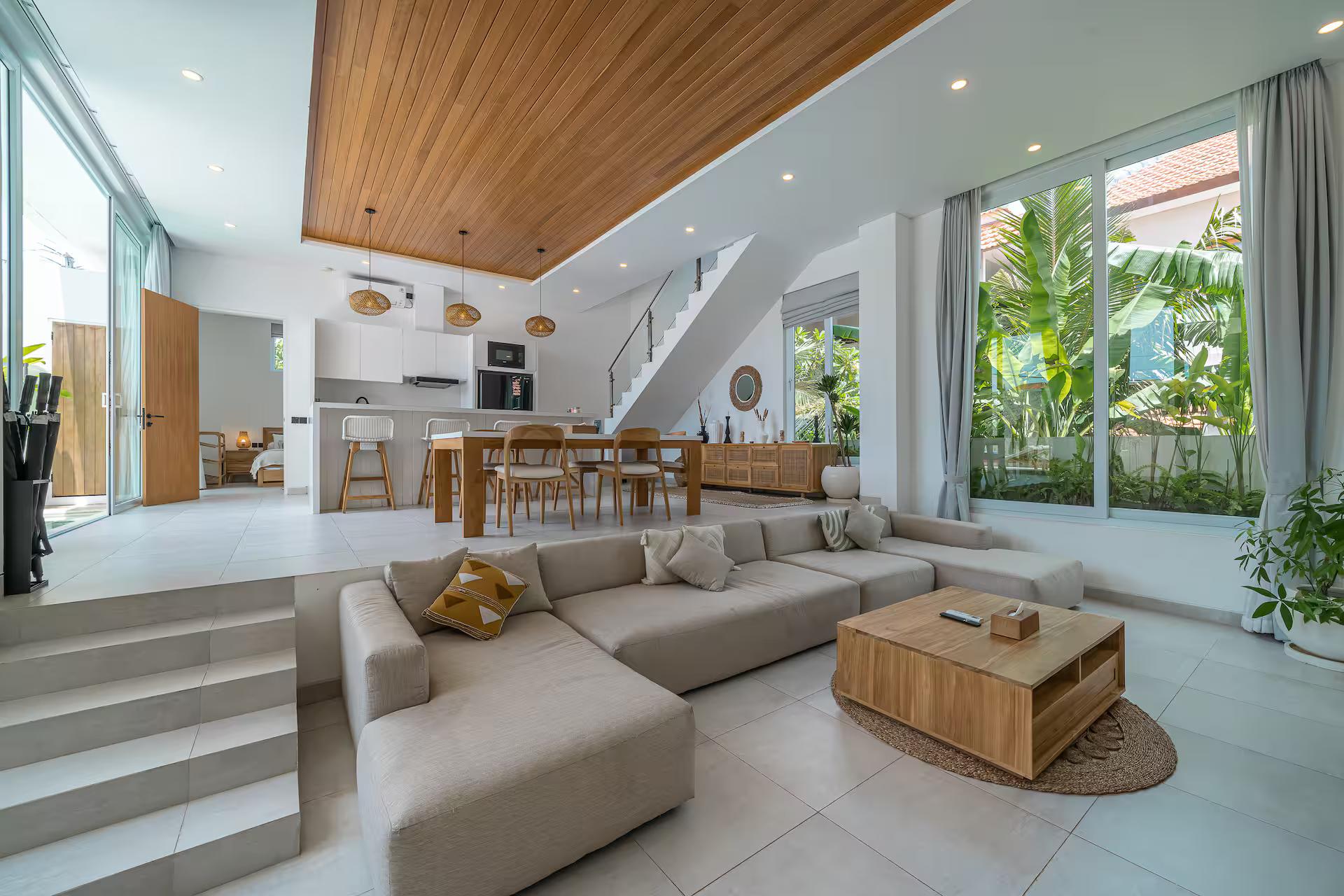The sunken living room at Villa Era under a double-height void and a timber ceiling raft