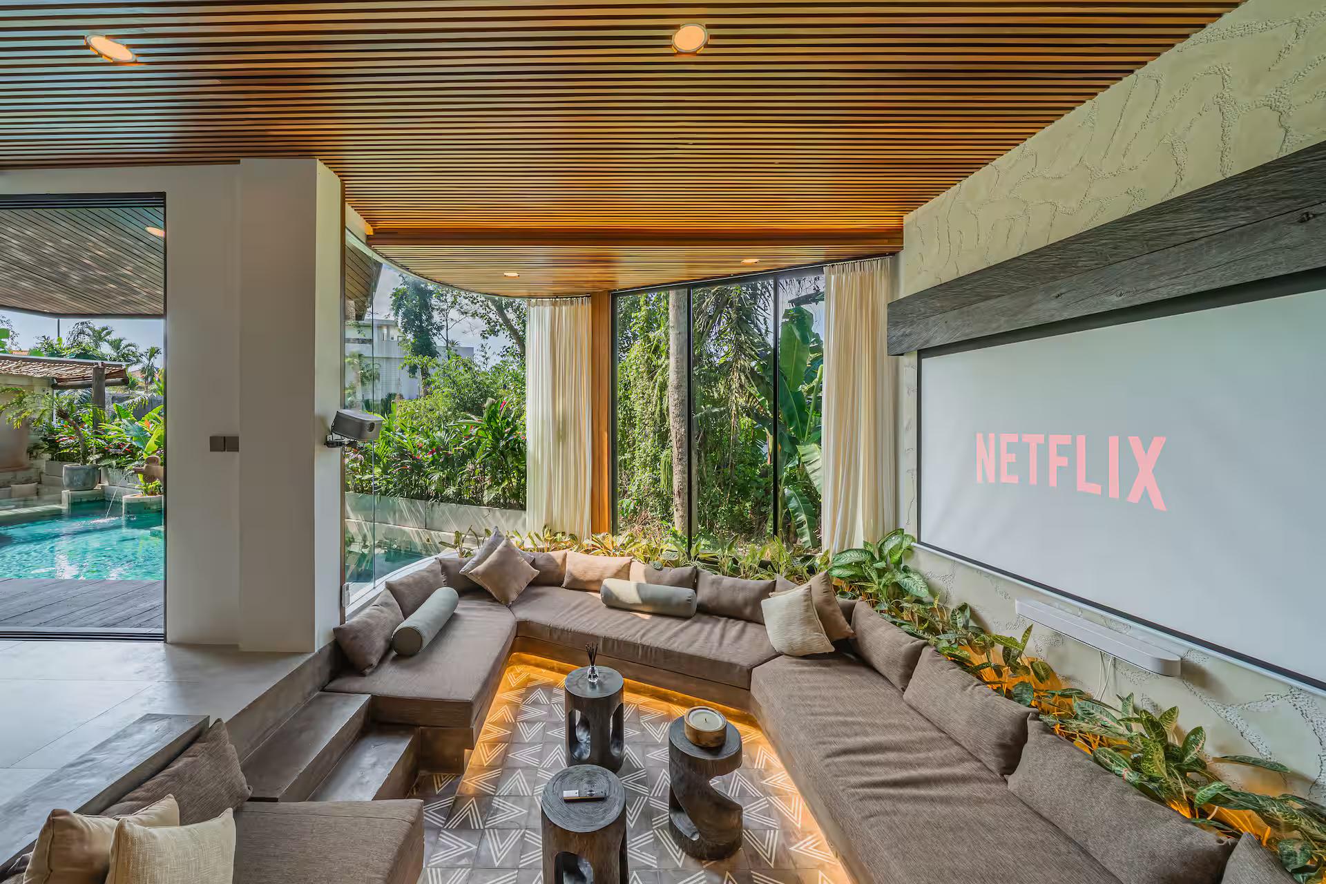 The sunken cinema lounge, its projector screen down and planting along the back edge