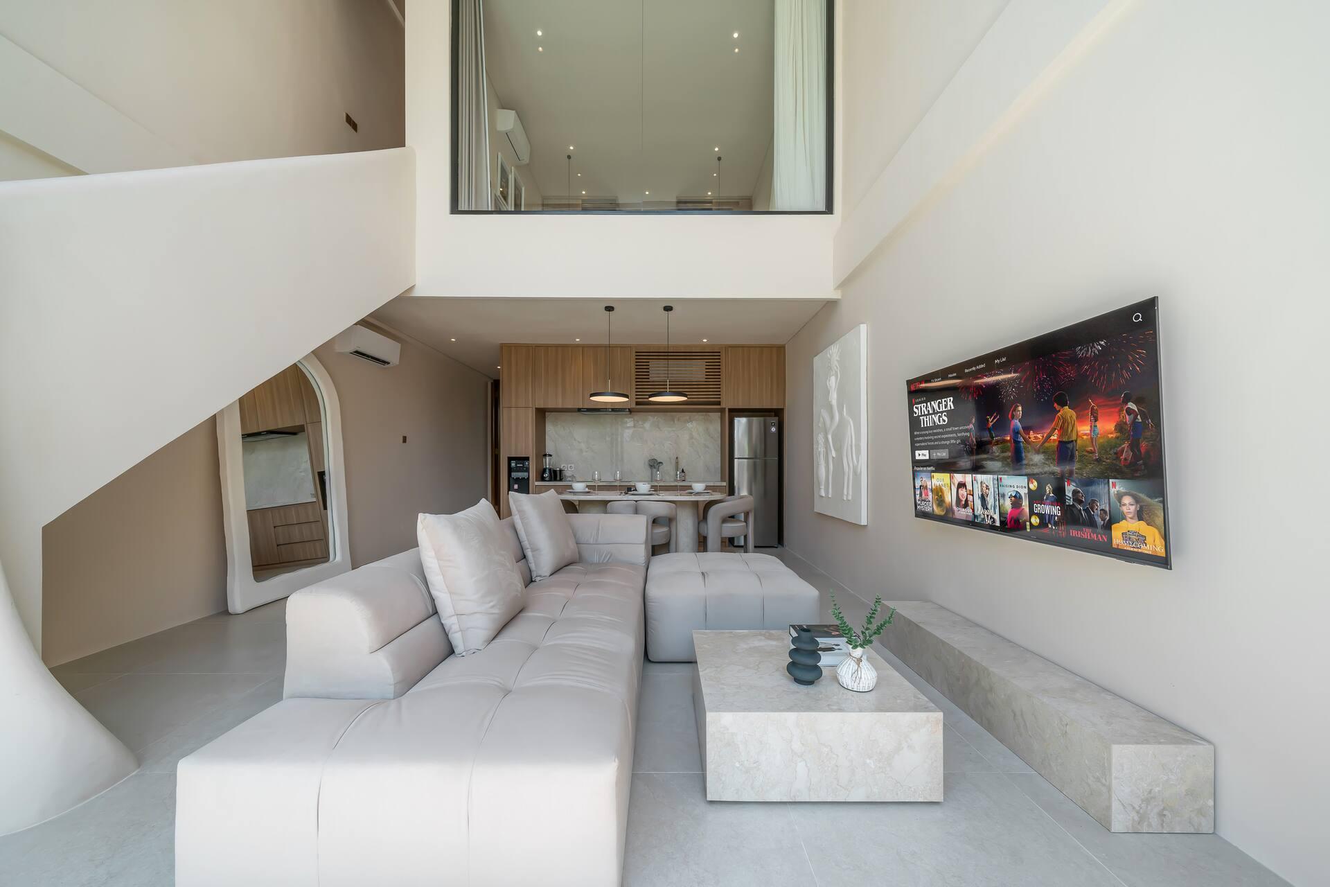 Double-height living room with a pale modular sofa, stone coffee table and a sculptural curved staircase