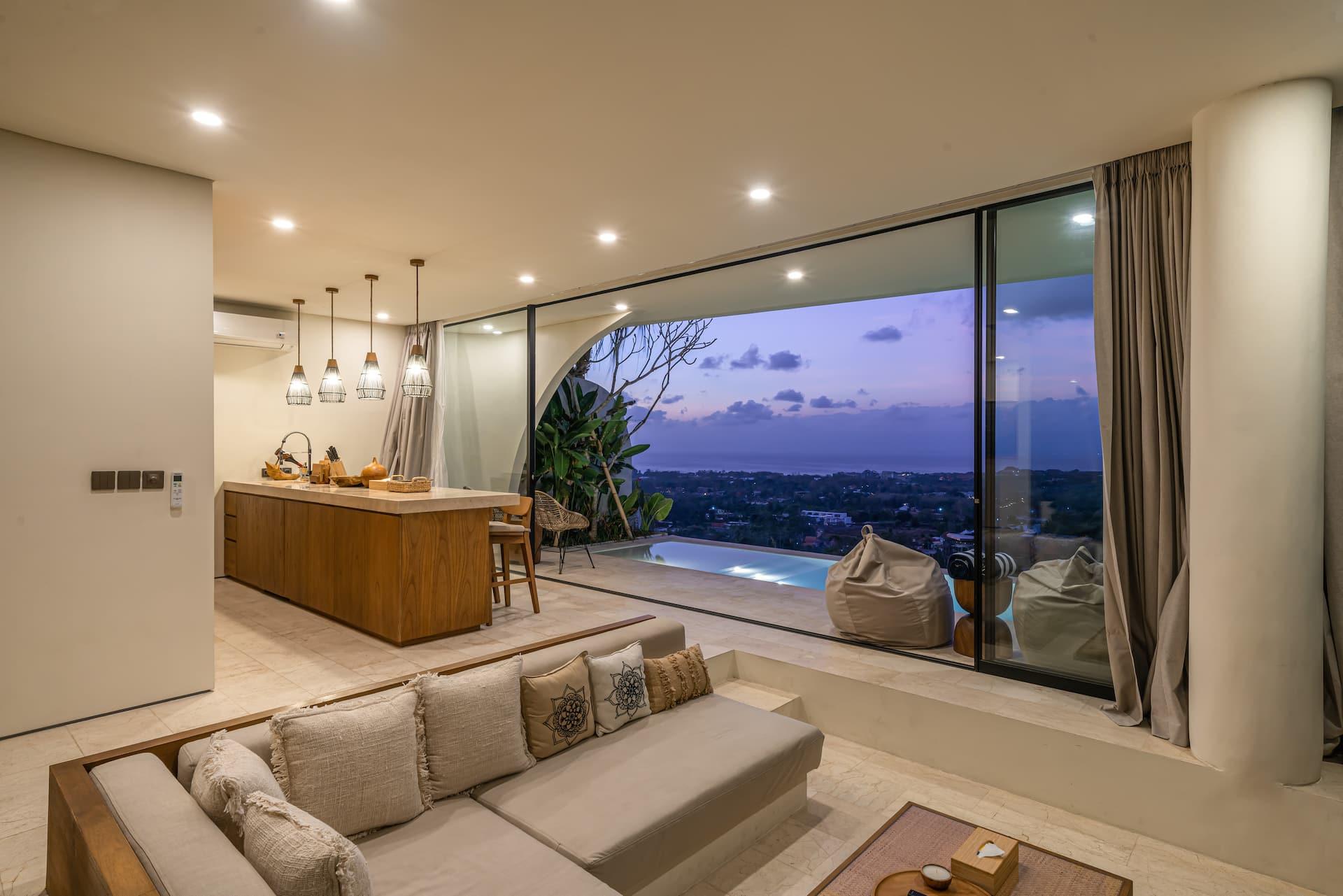 Sunken lounge with built-in cream sofas facing the pool and a sweeping sea-view panorama