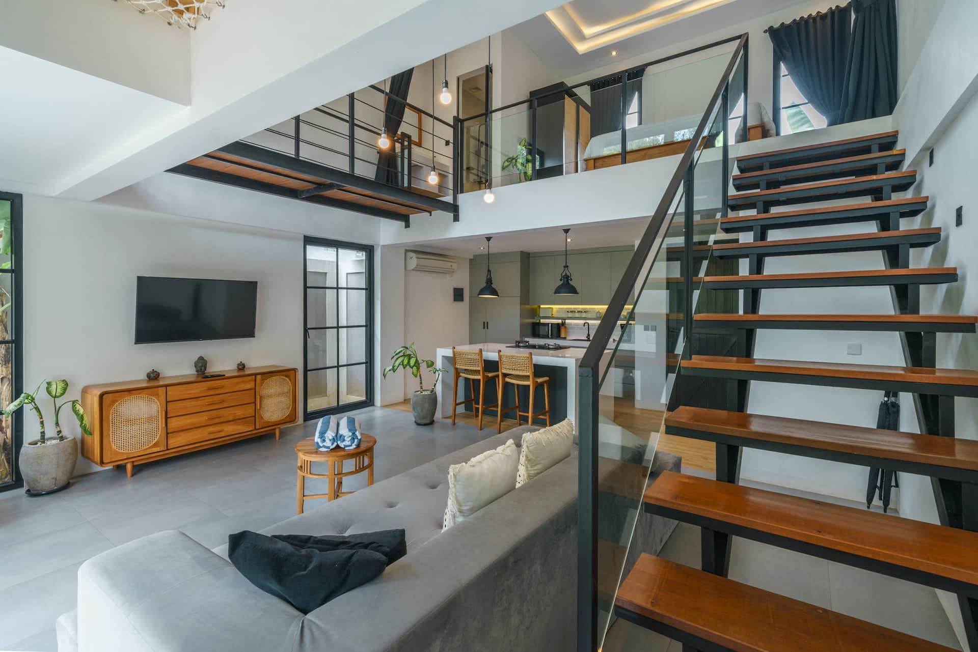 Double-height living room at Loft Valentin with a floating timber staircase and a grey sofa