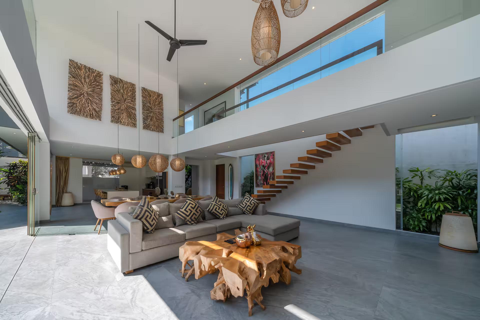 Double-height living room with a driftwood table and an open timber staircase