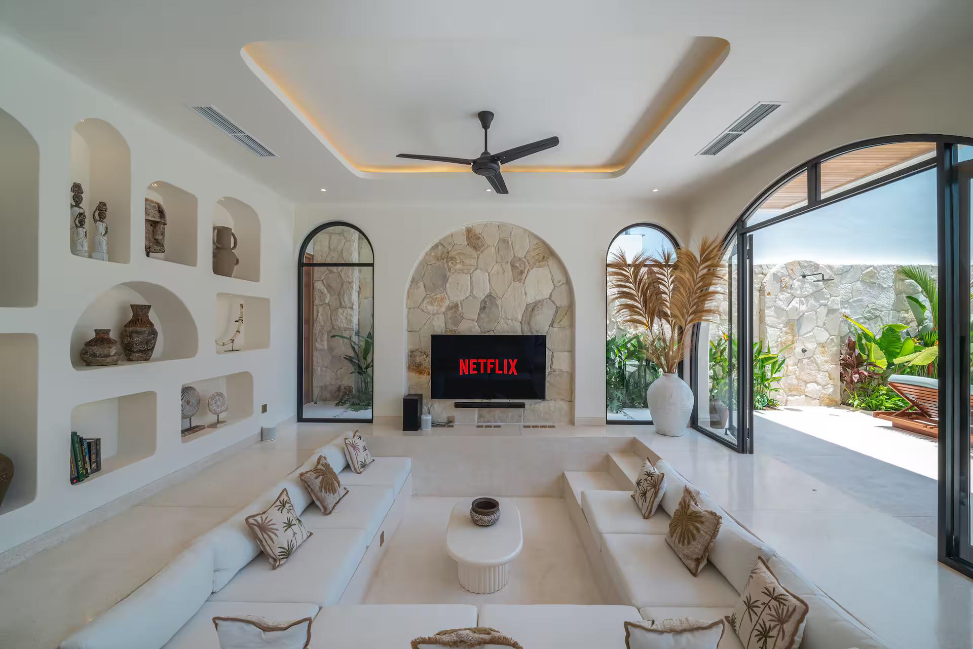 Sunken lounge at Villa Bimini, white sectional below arched niches and a rough stone wall
