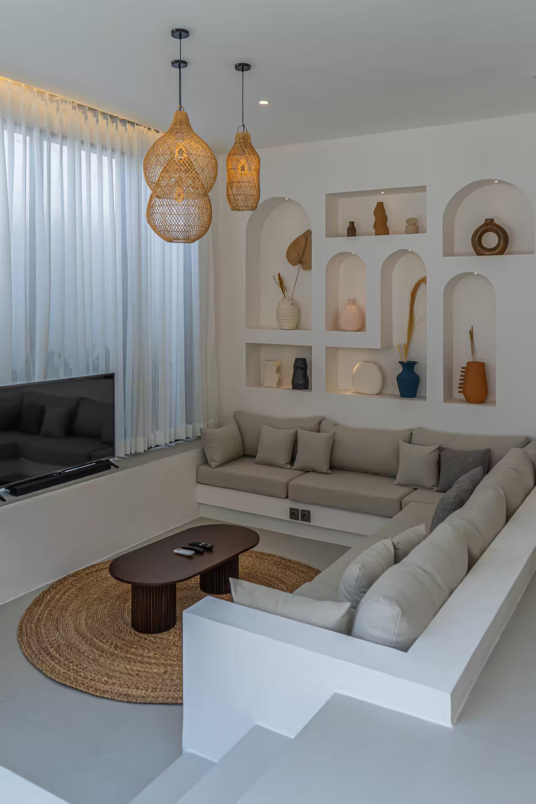 Step-down linen banquette below a bank of arched display niches, jute rug and low timber table