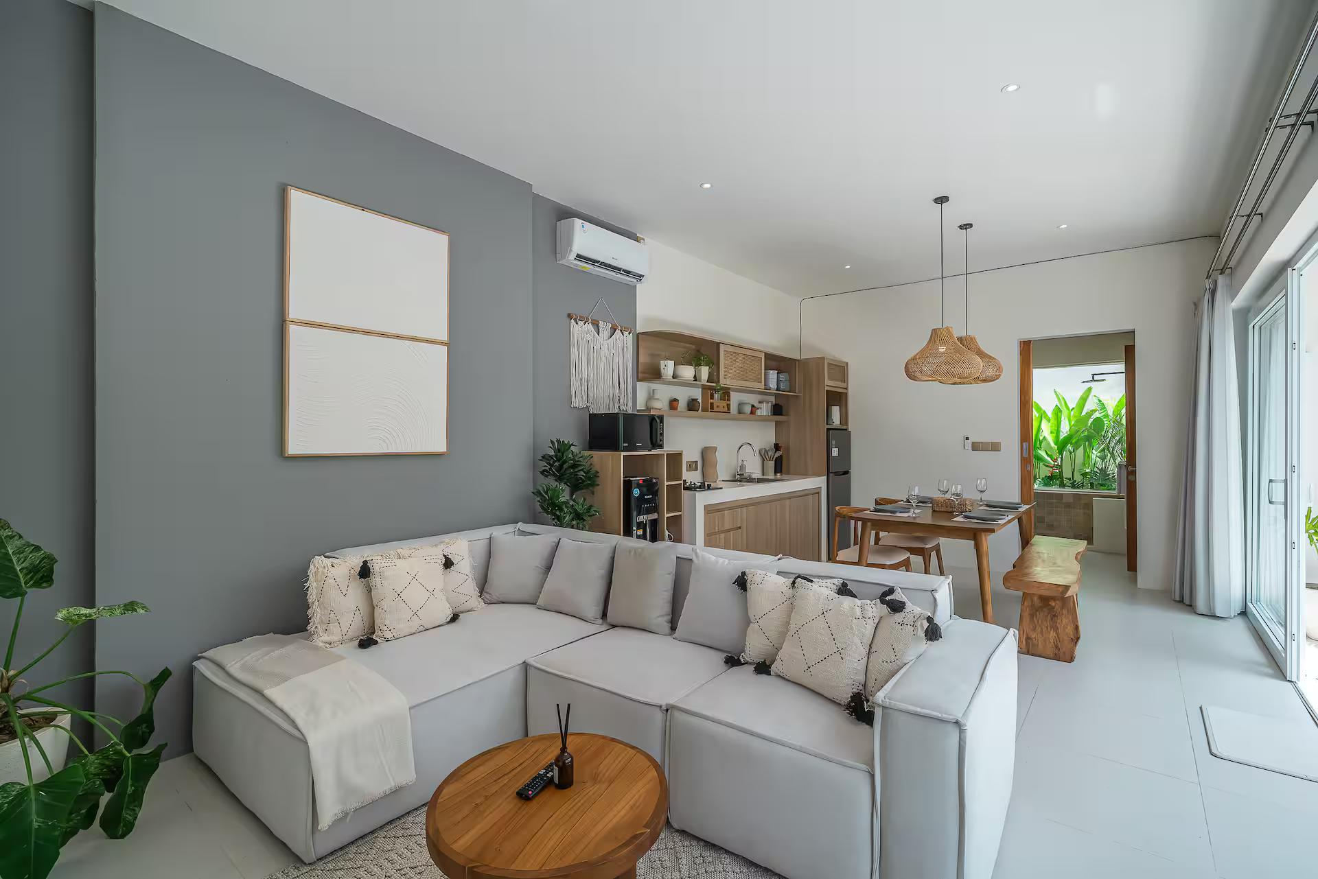 Pale sectional sofa and round timber table in the open living room at Villa Gajah
