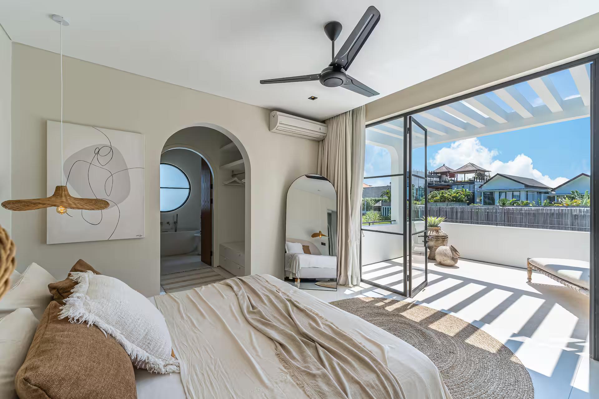 Bedroom with glass doors folded open to a private balcony and the morning light