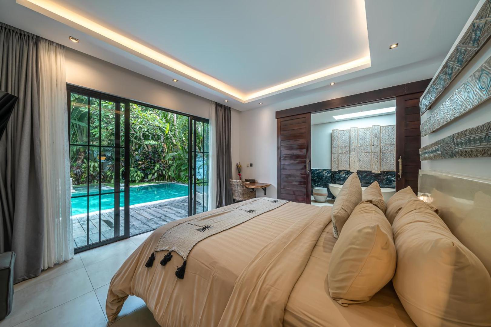 Bedroom in sand and cream with sliding glass doors opening straight onto the pool deck