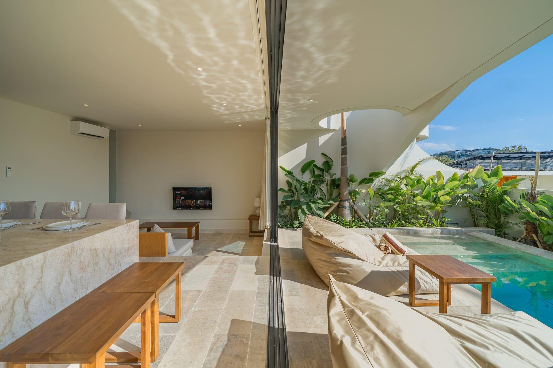 Villa Amber's living pavilion opening straight onto the pool terrace through full-height glass