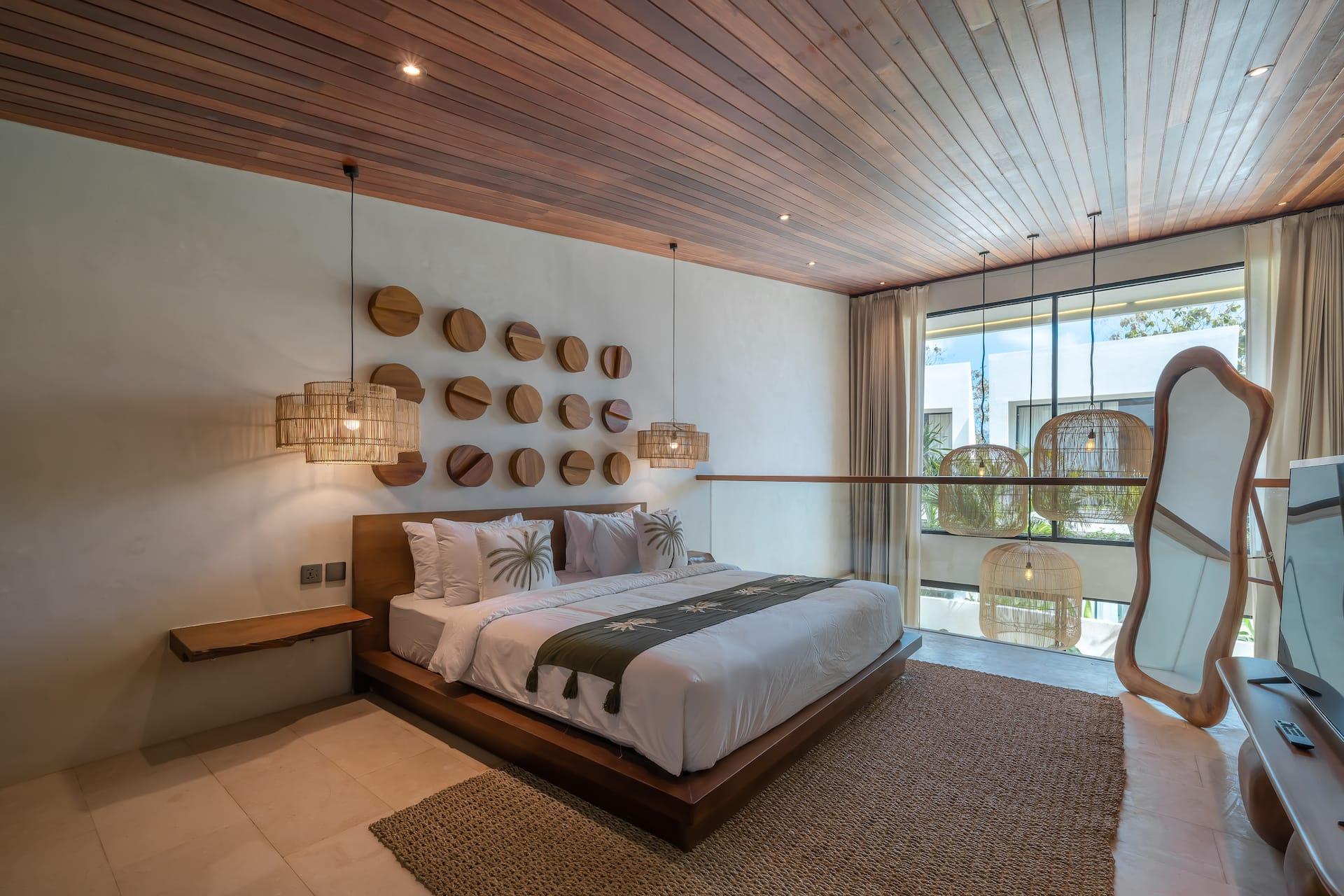 Mezzanine king bedroom at Villa Elementa, timber ceiling and carved wooden discs above the bed