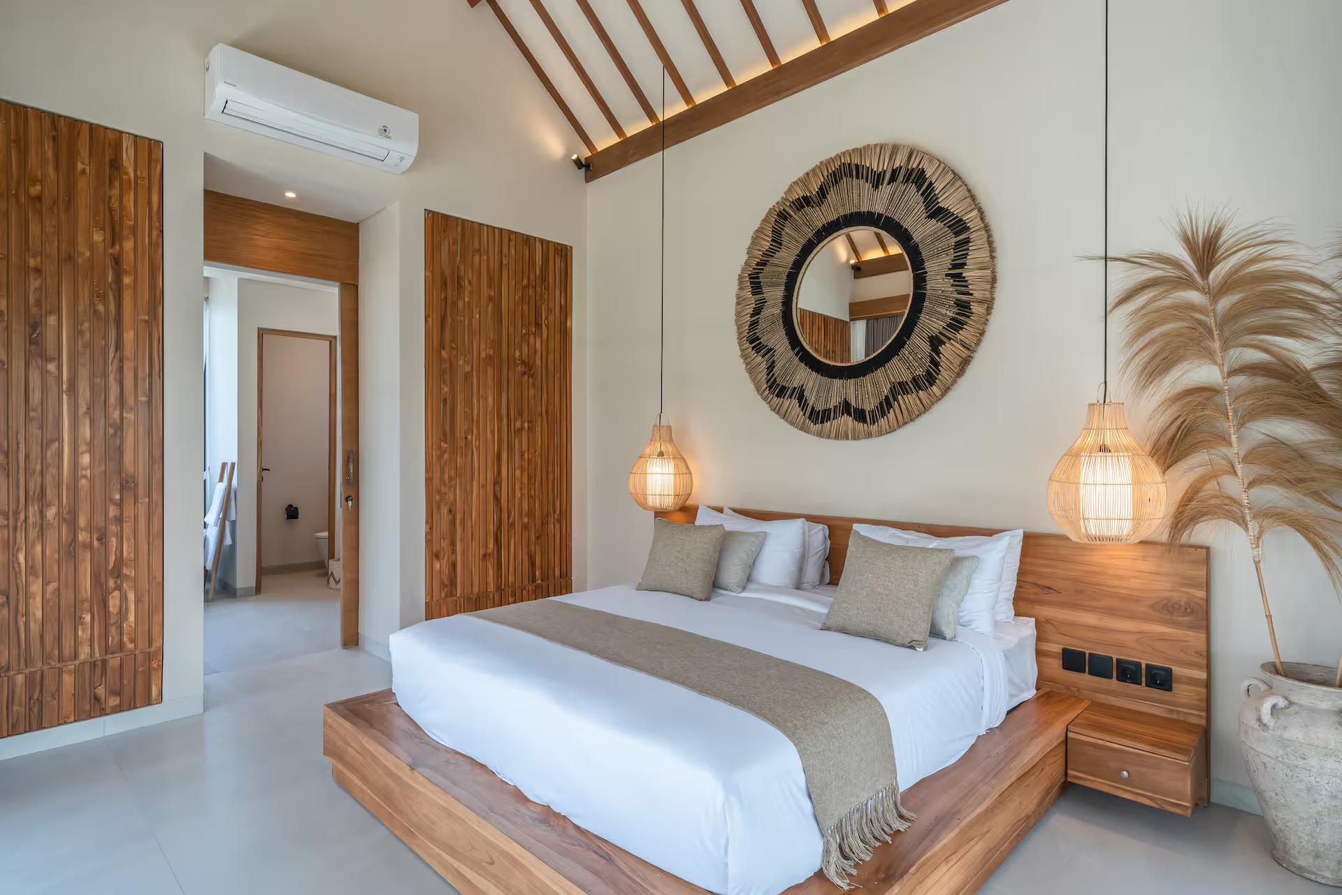 Master bedroom at Villa Saya under a split-bamboo ceiling, with a round woven mirror above the bed
