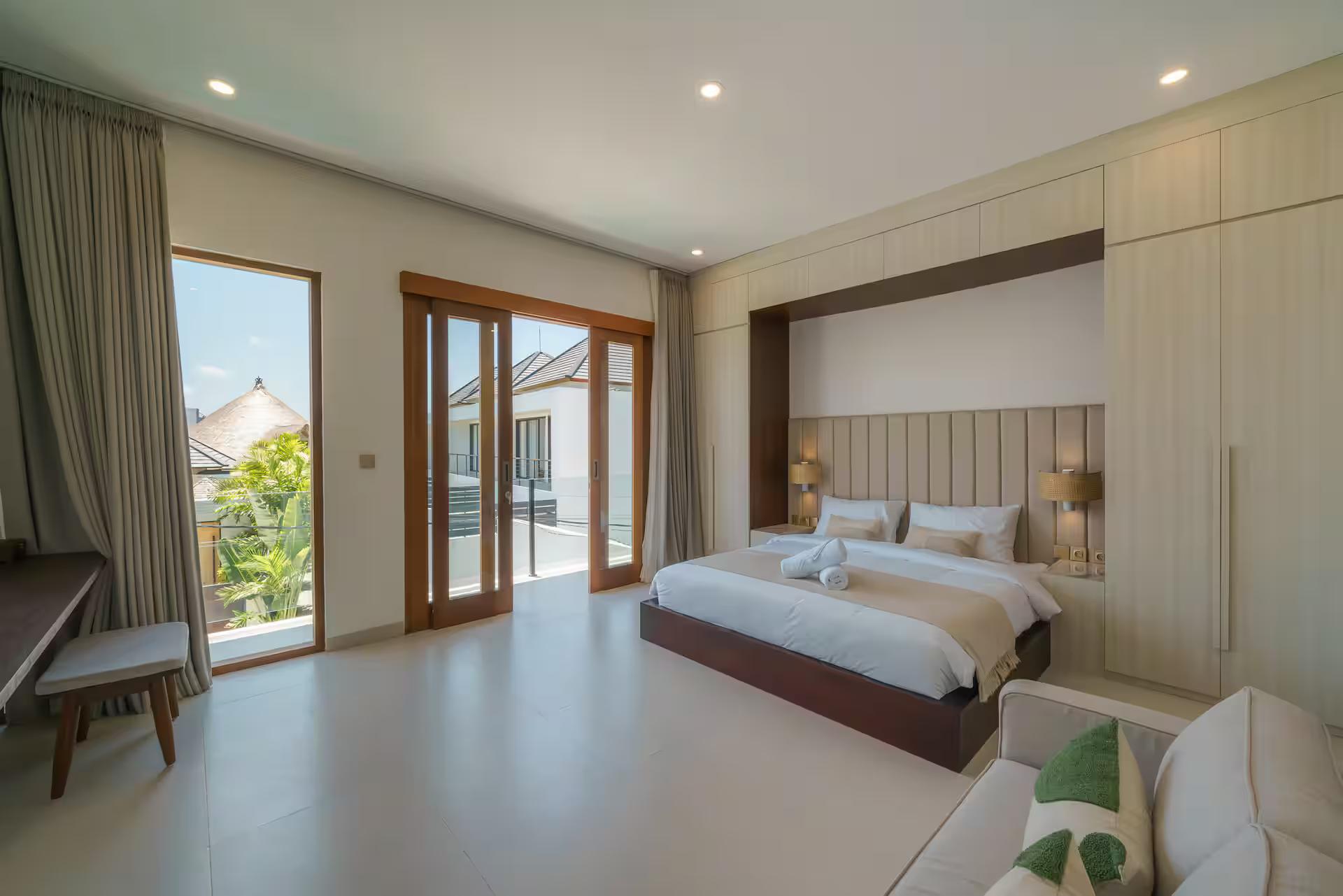 King bedroom with a fluted timber headboard and doors opening to a balcony