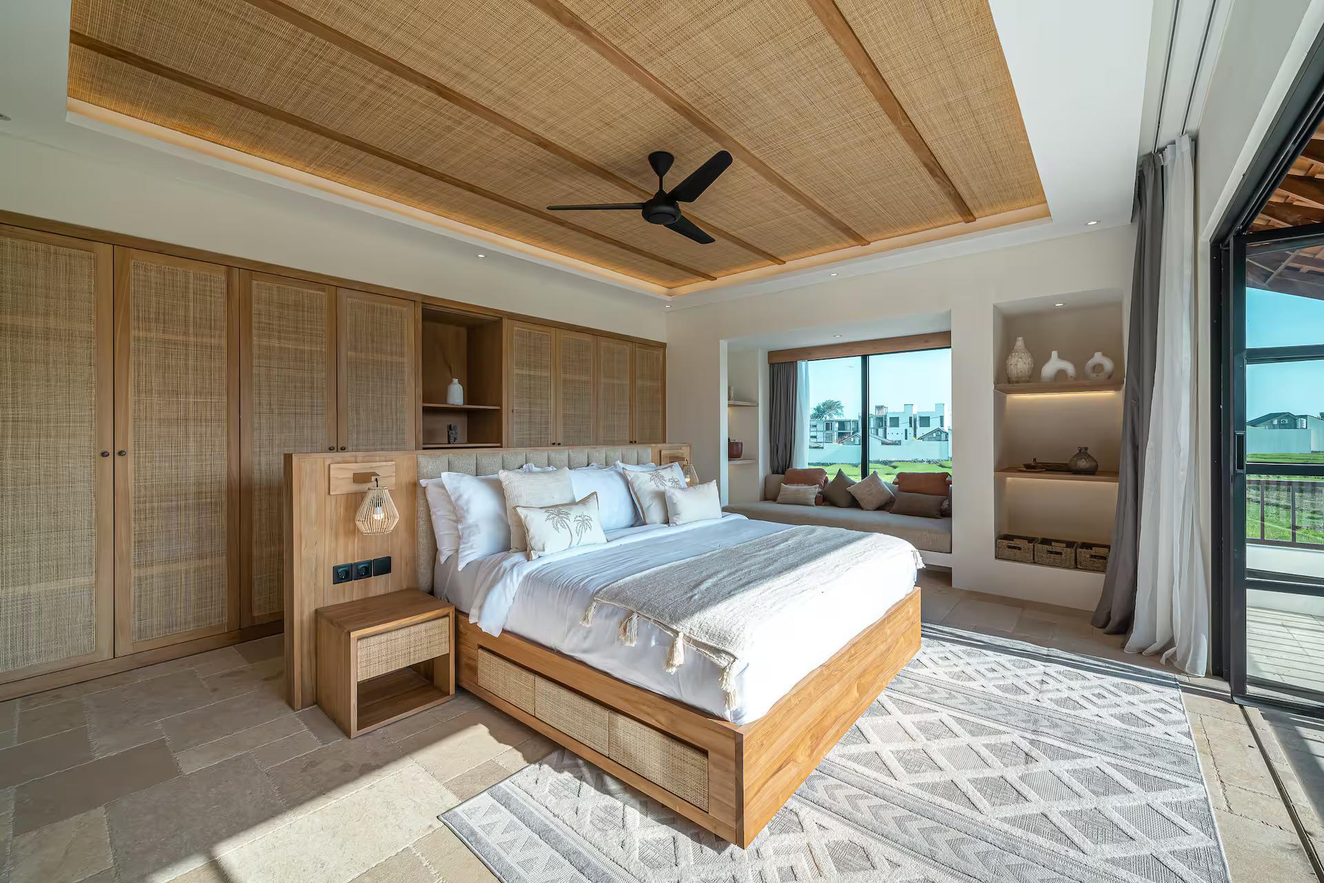 Master bedroom under a split-bamboo ceiling, timber platform bed and glass onto the balcony