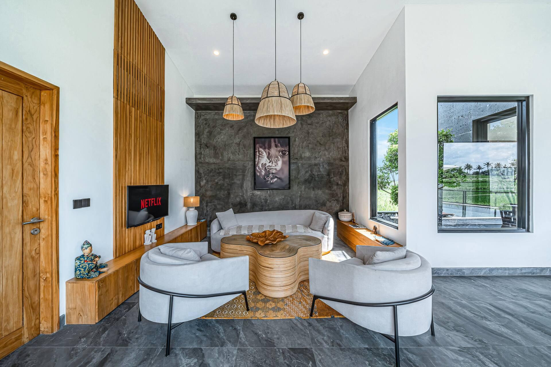 Open-plan living pavilion with curved cream sofas under three oversized rattan pendants