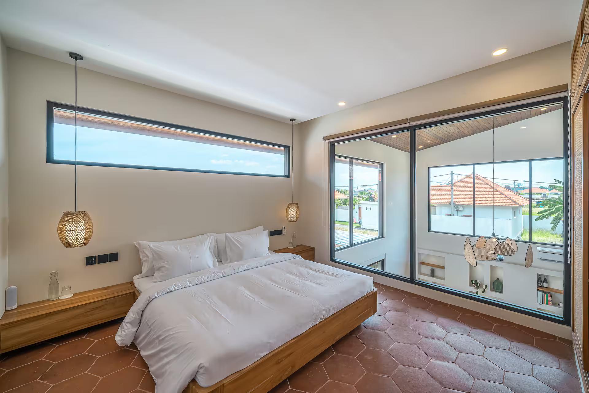 King bed at Villa Fonda facing a glass wall, terracotta hexagons underfoot