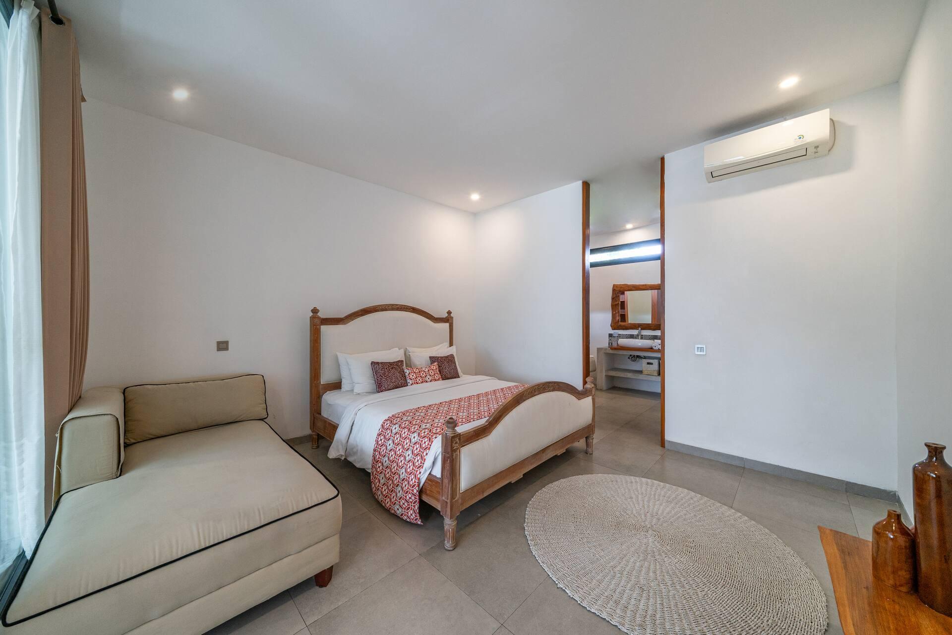 Ground-floor bedroom with a carved timber bed and an upholstered chaise at its foot