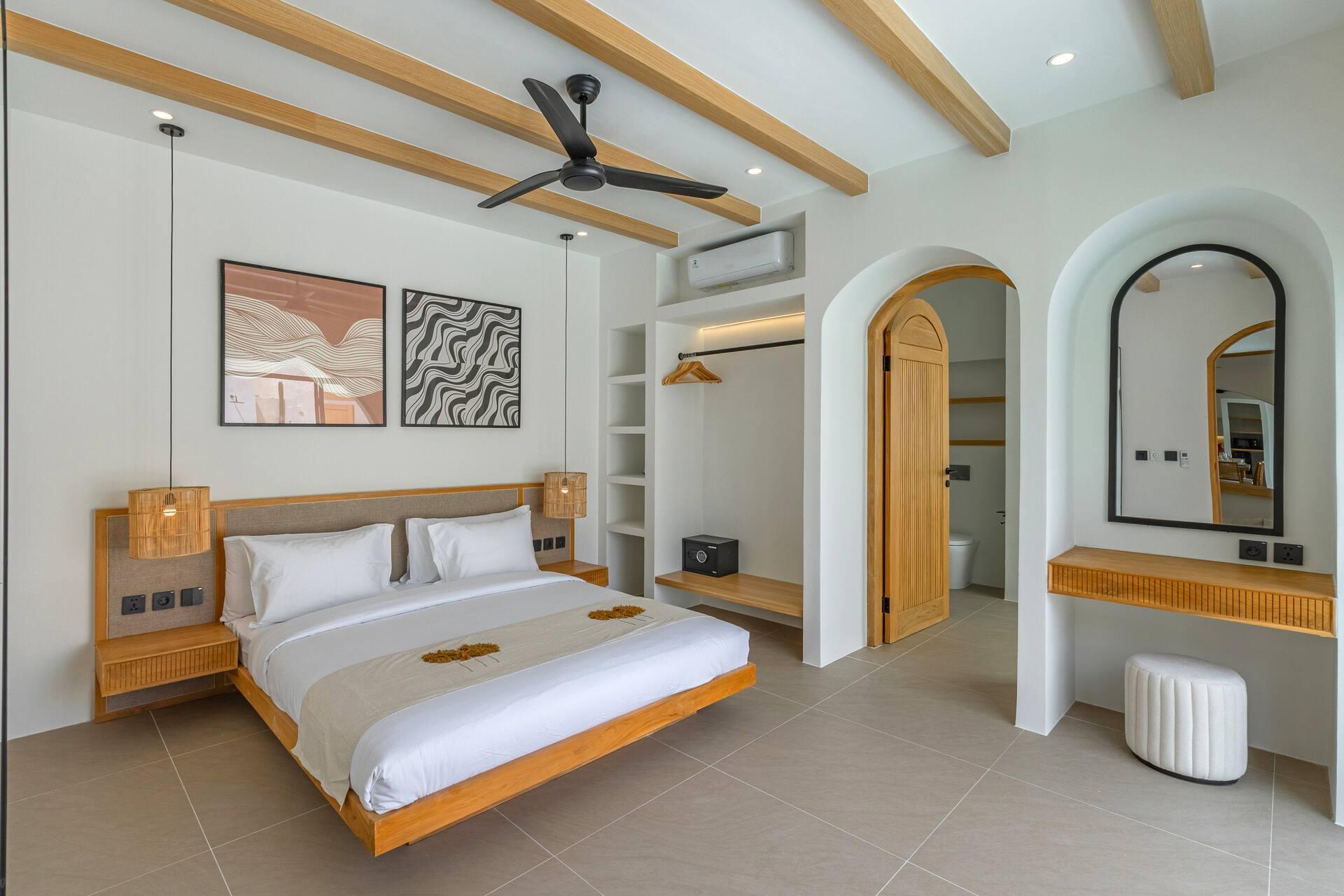 Bedroom with a floating timber bed, rattan pendants, abstract prints and an arched vanity mirror