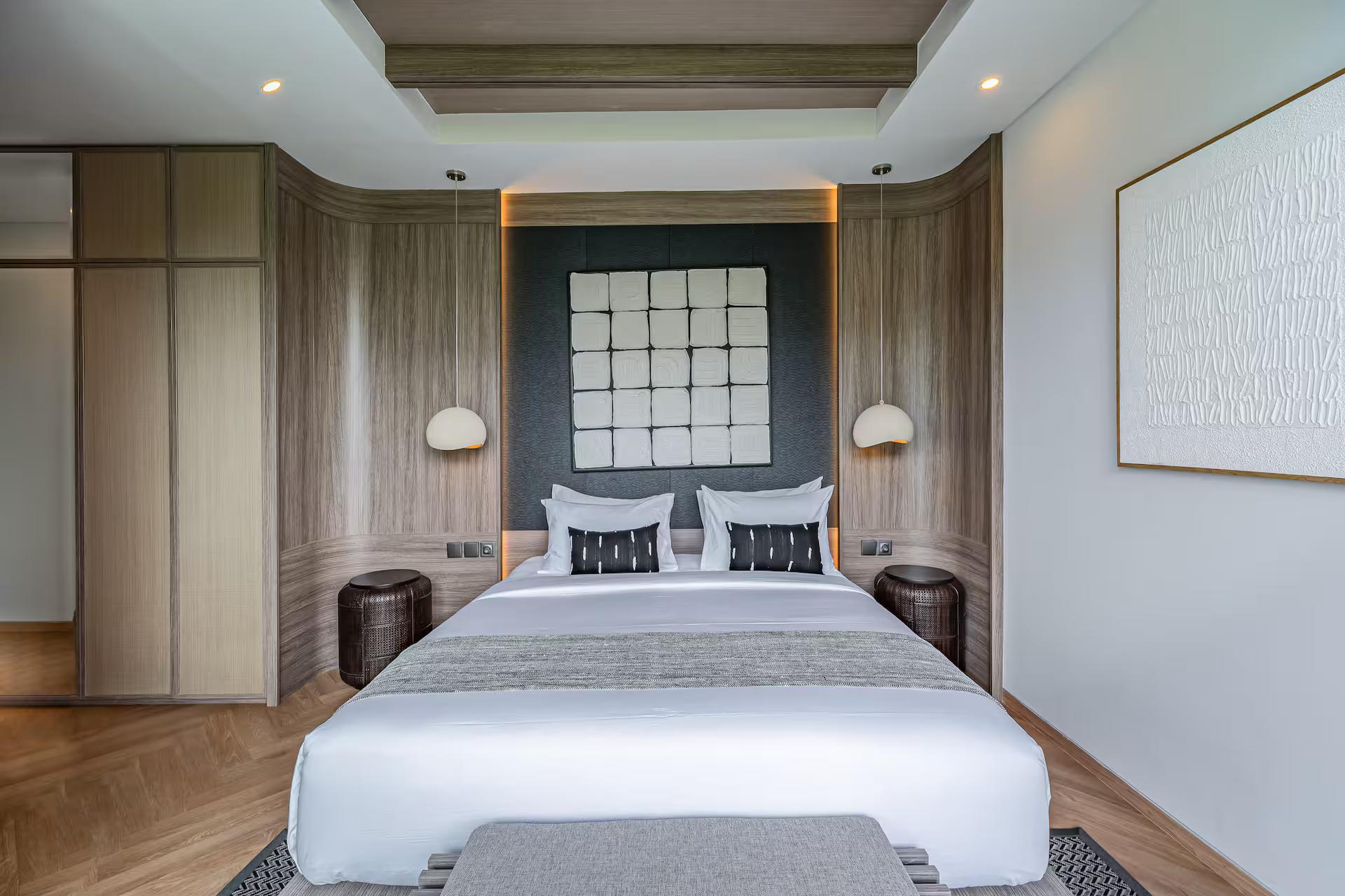 King bedroom with a grid of dark panels behind the bed and paper wall lights