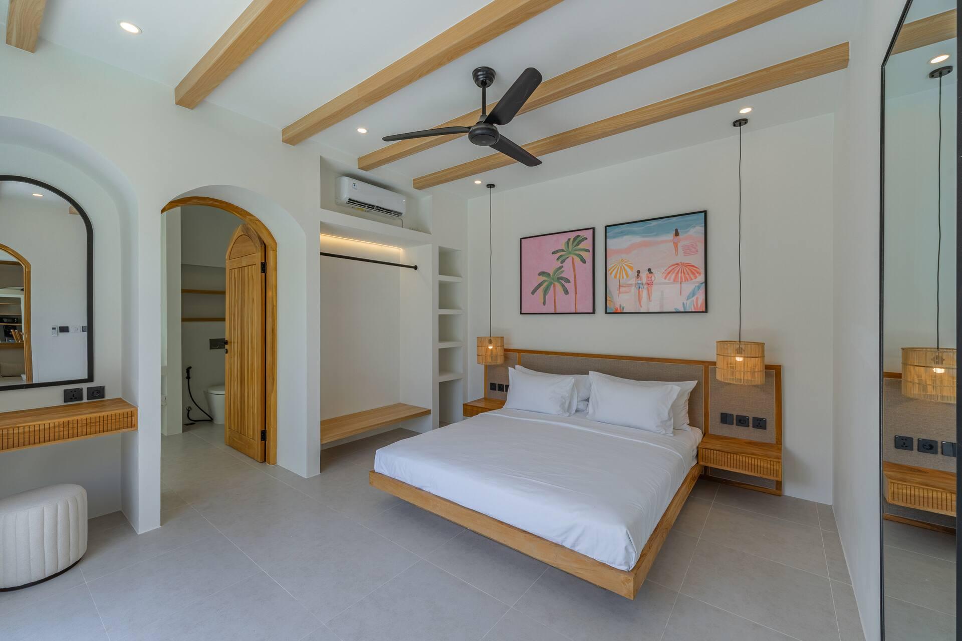 Bedroom with a floating timber bed, rattan pendants and pink palm-tree prints above the headboard