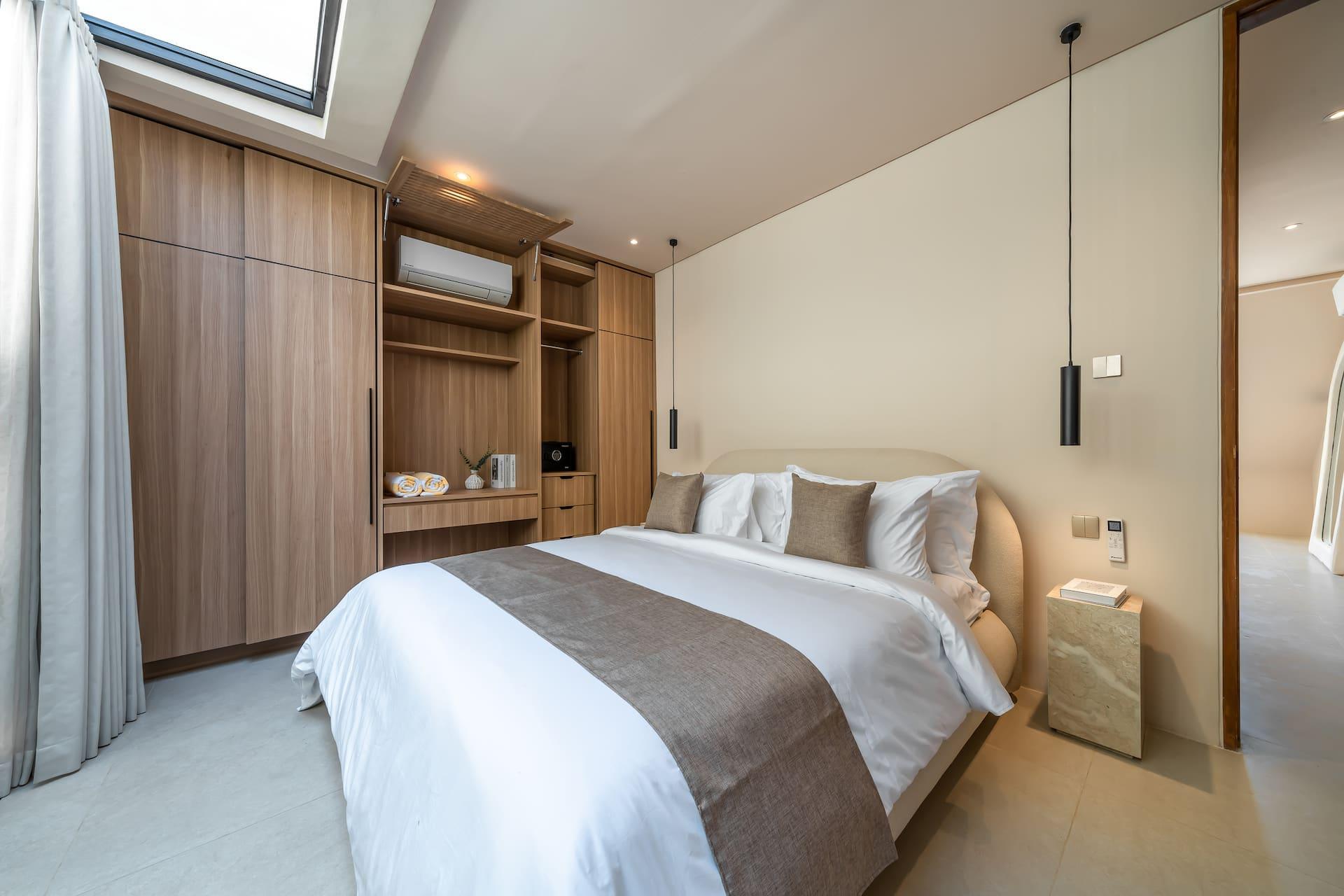 Bedroom at Enso 6 with a curved upholstered headboard, timber wardrobe wall and a slim black pendant