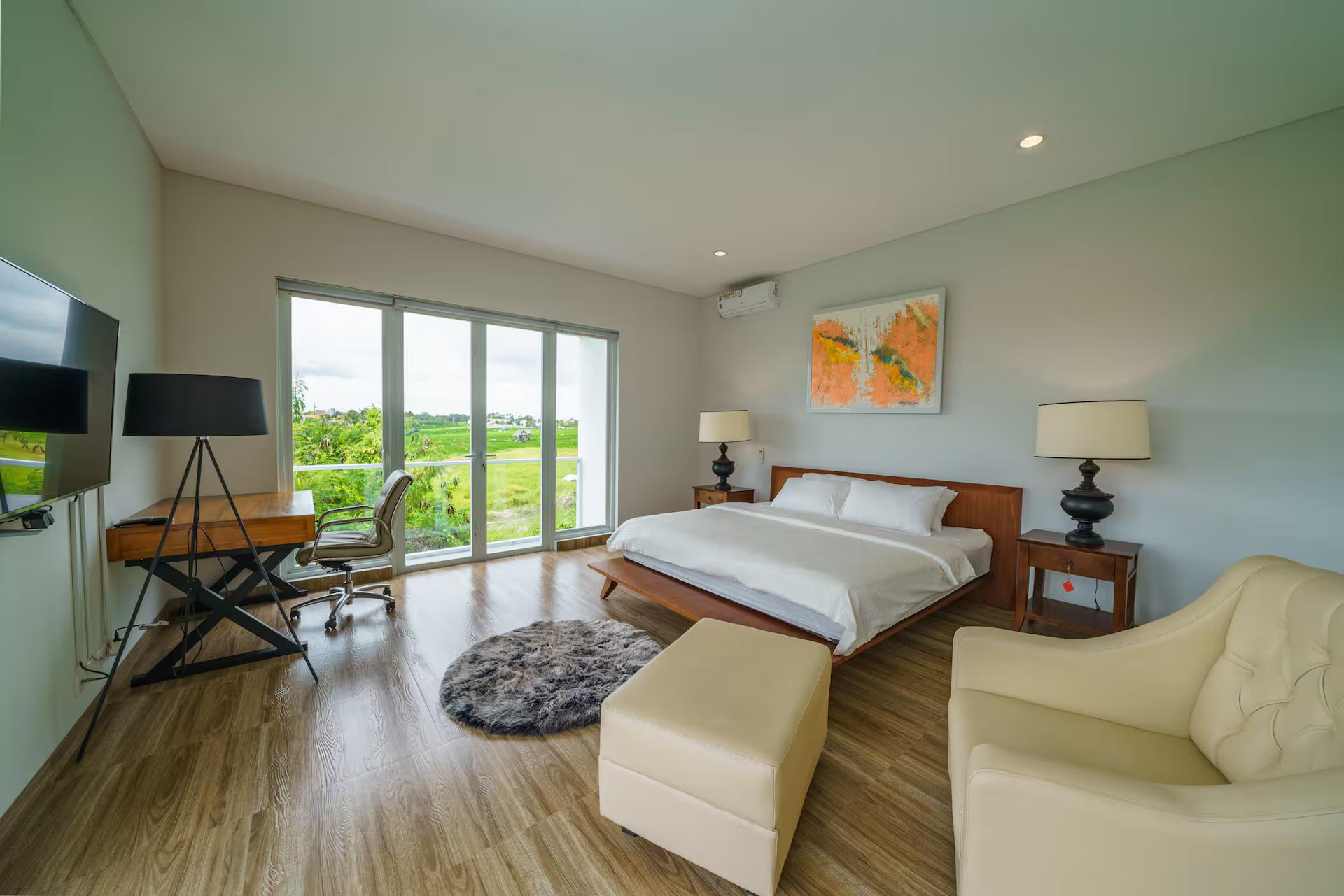 Bedroom at Villa Ammanya with a desk under the window and rice fields beyond the glass