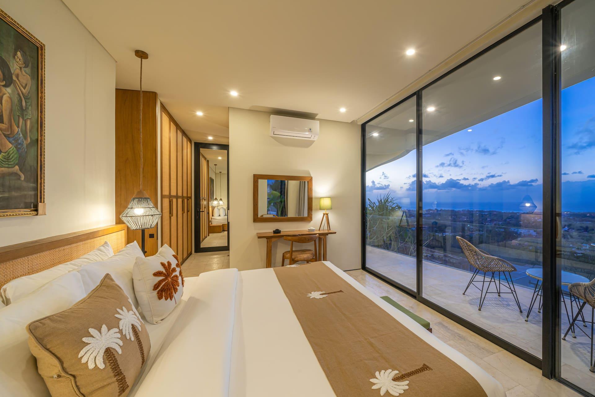 Villa Amanecer bedroom with floor-to-ceiling glass opening to a balcony with sea views