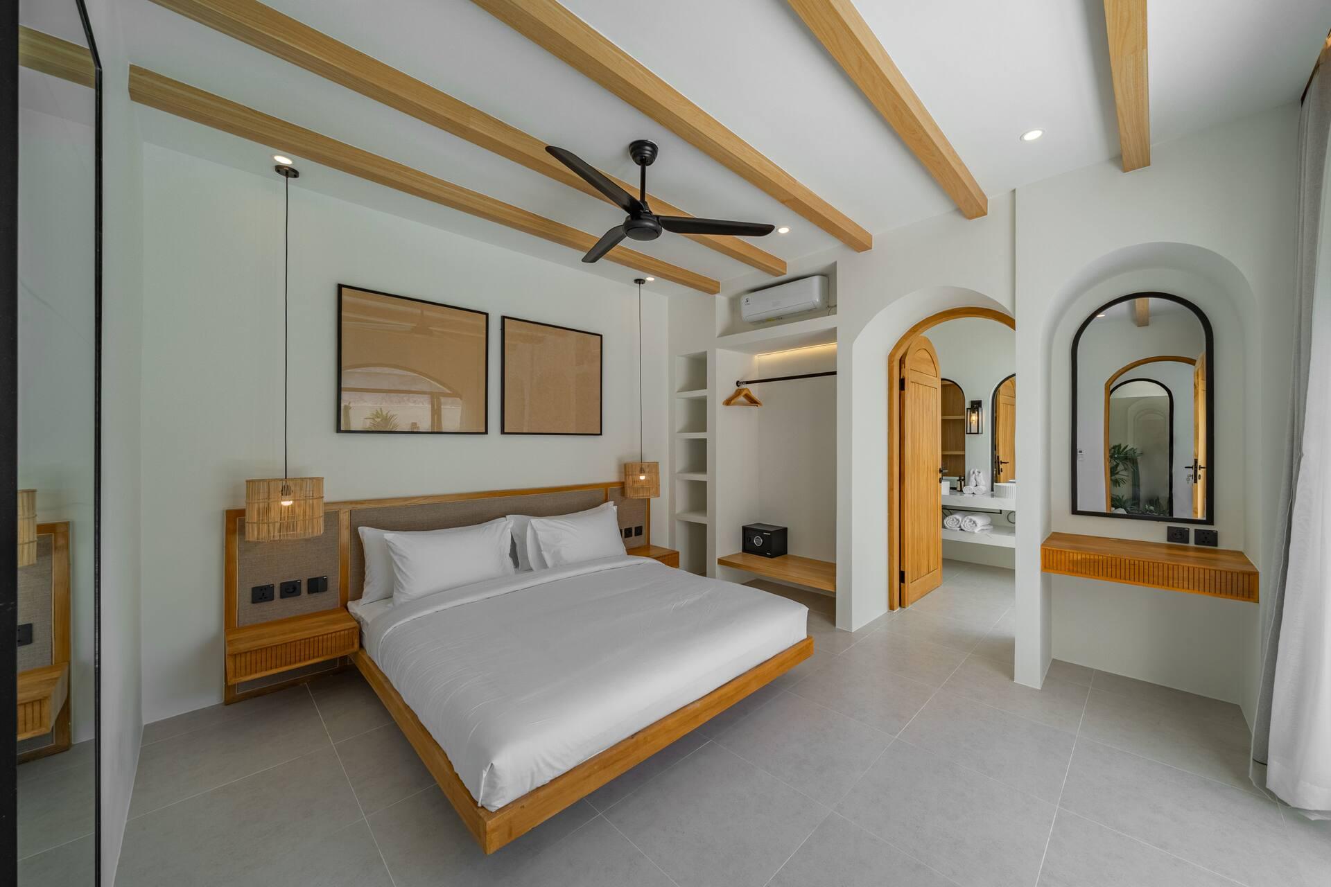 Villa Sorrento One bedroom with a queen bed, timber ceiling beams and an arched mirror