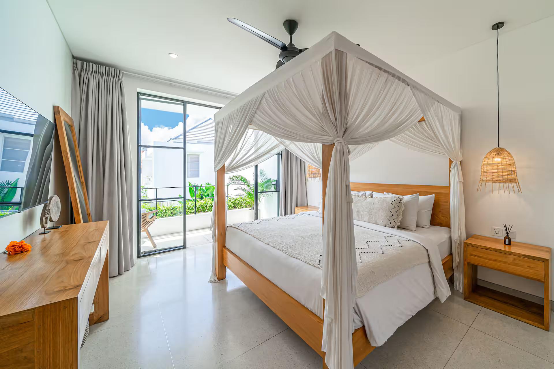 The master bedroom at Villa Puri Senang, a teak four-poster under a white canopy net