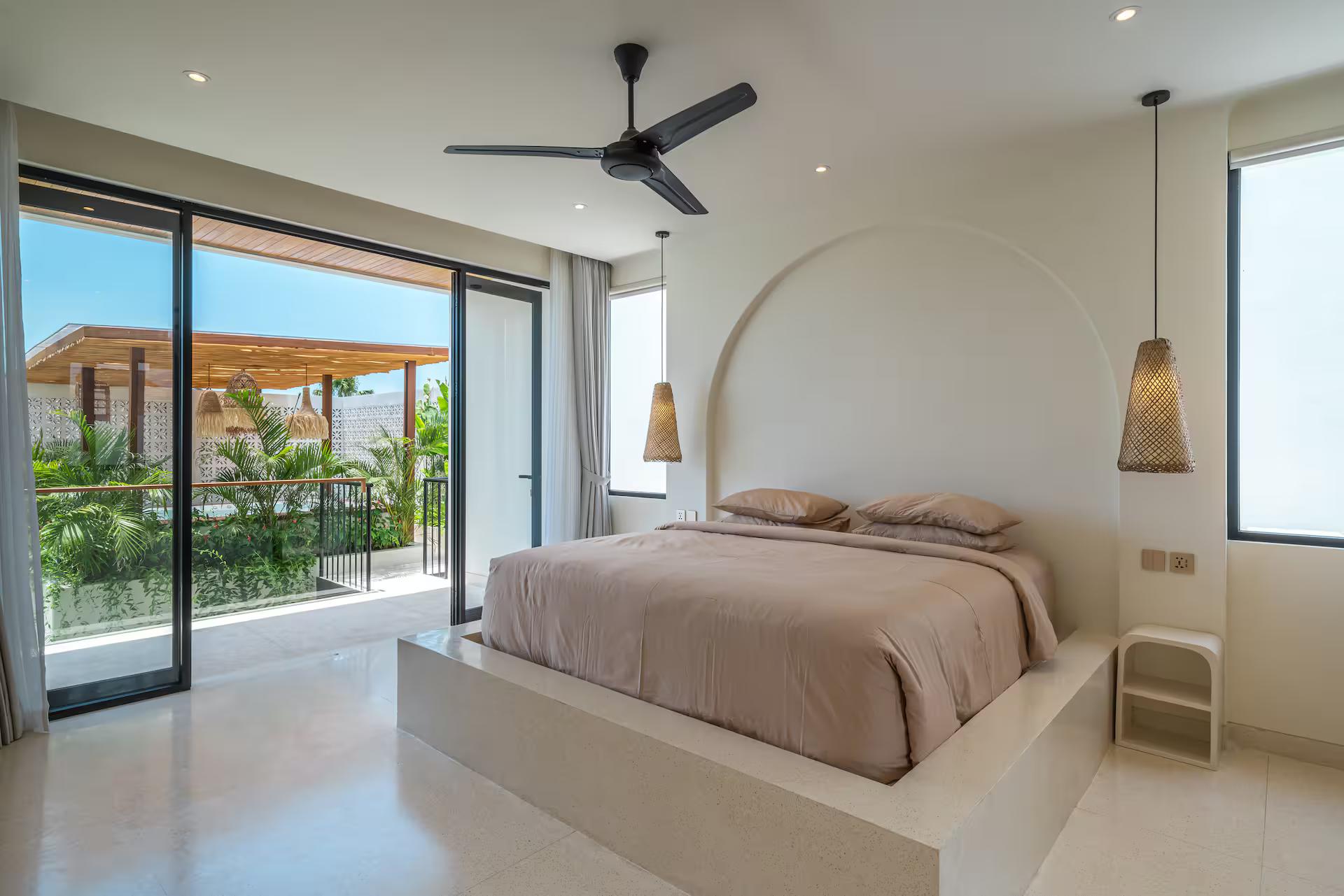 Master bedroom with the bed on a rendered platform and glass doors to the upper terrace