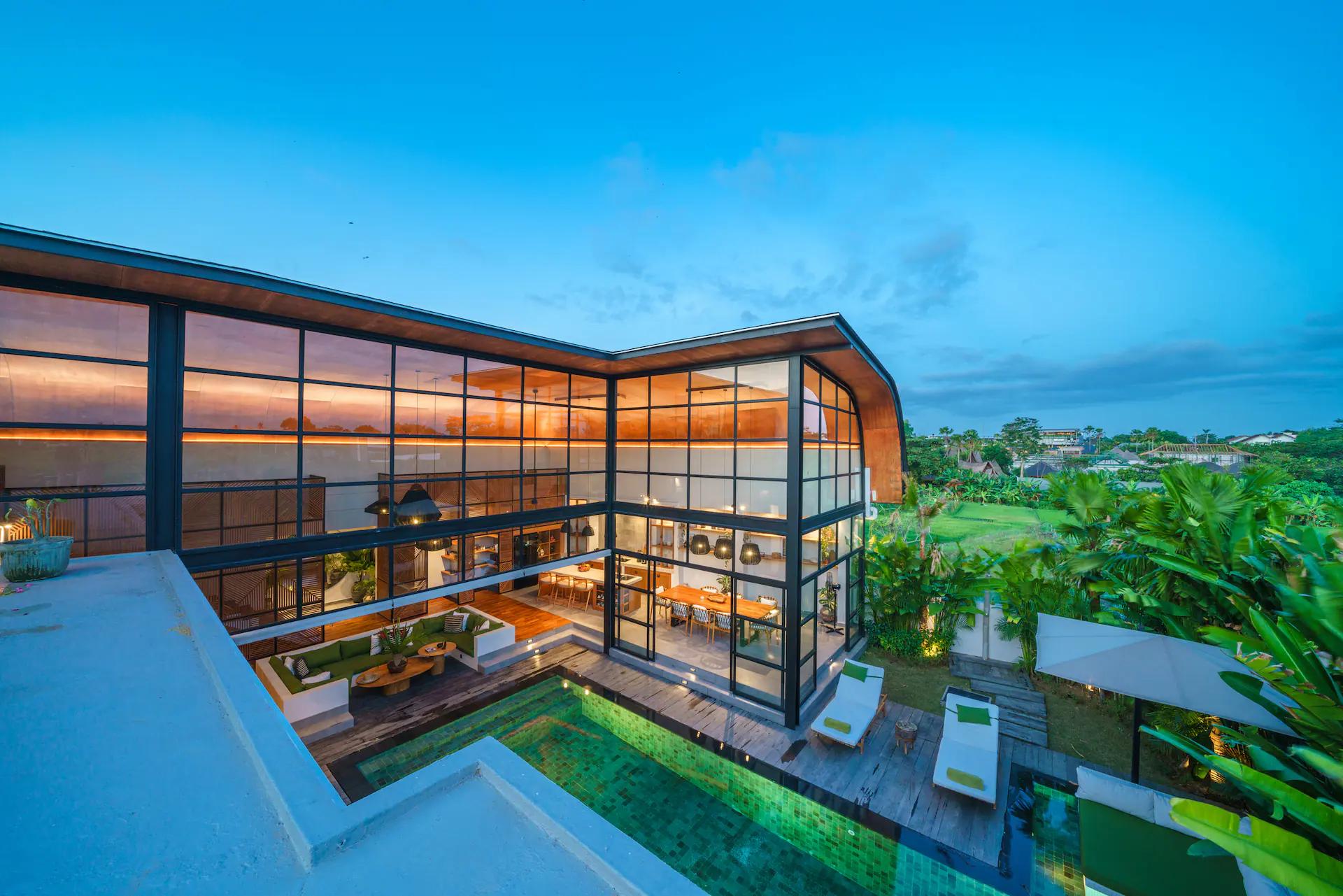 Villa Mango Bliss at dusk, its curved roof and full-height glazing above the pool