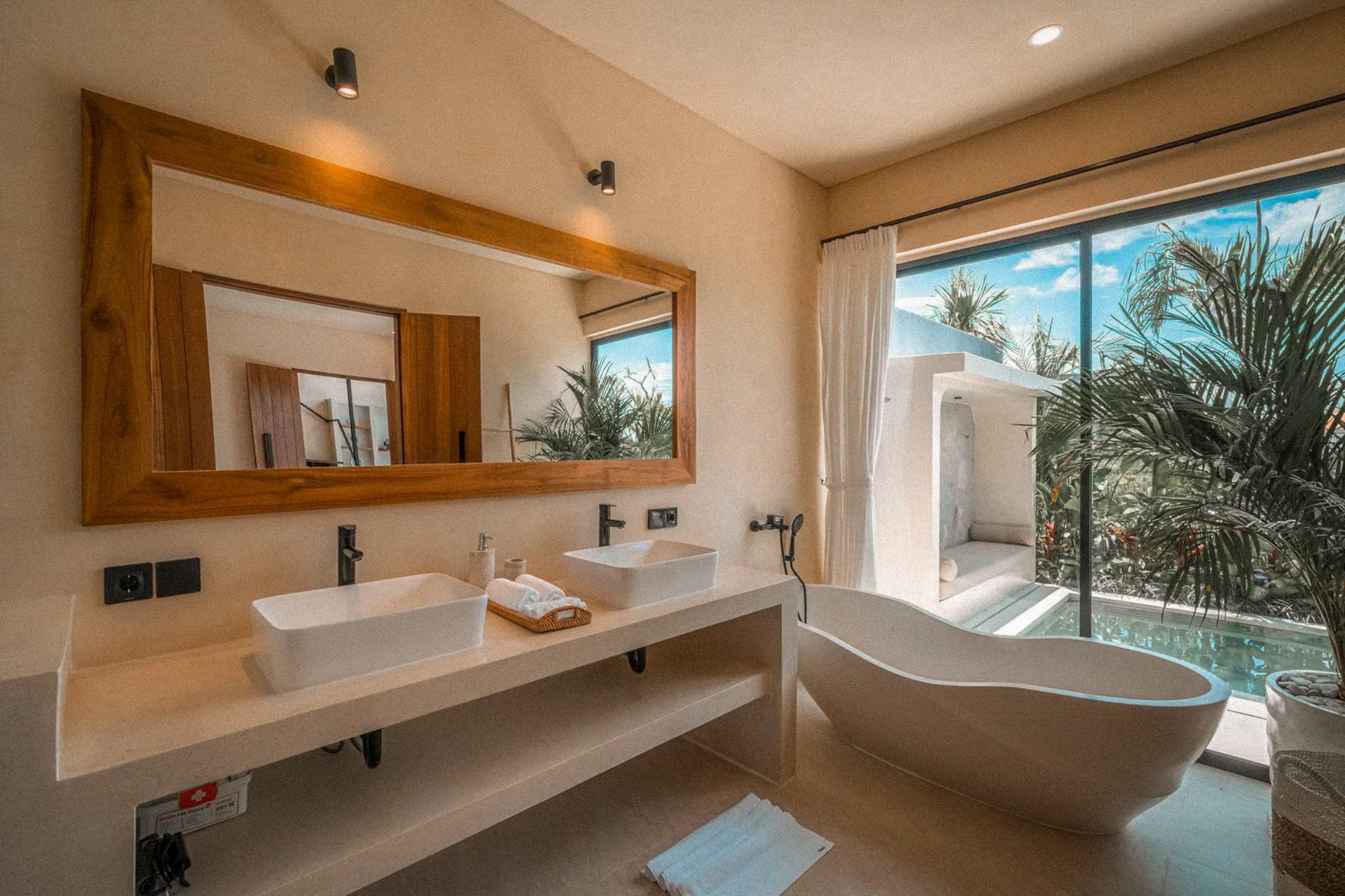 Twin basins under a broad timber mirror and a freestanding stone tub by the window
