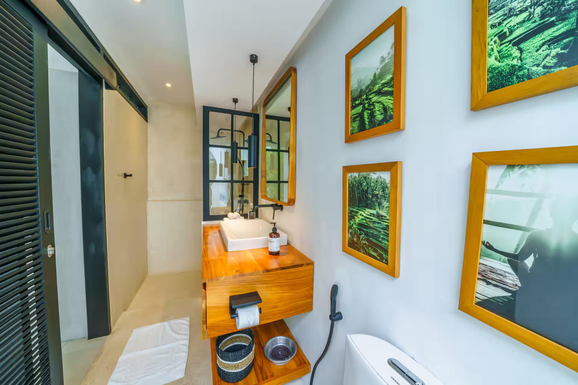 Bathroom with a timber vanity, black tapware and a wall of framed botanical prints