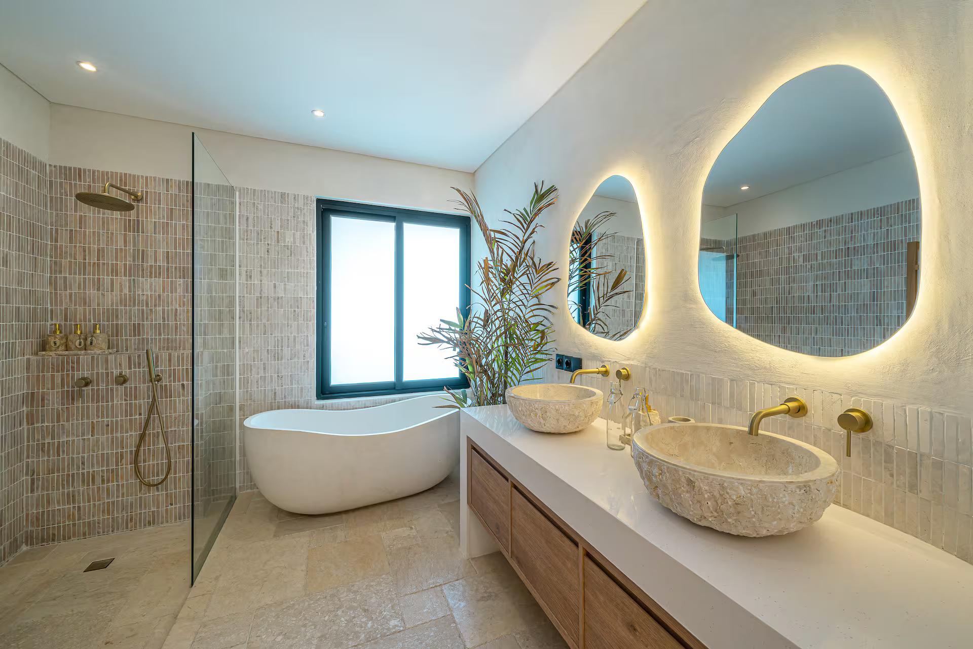 En-suite at Sunbeam Oasis with a stone freestanding tub, mosaic tile and backlit organic mirrors