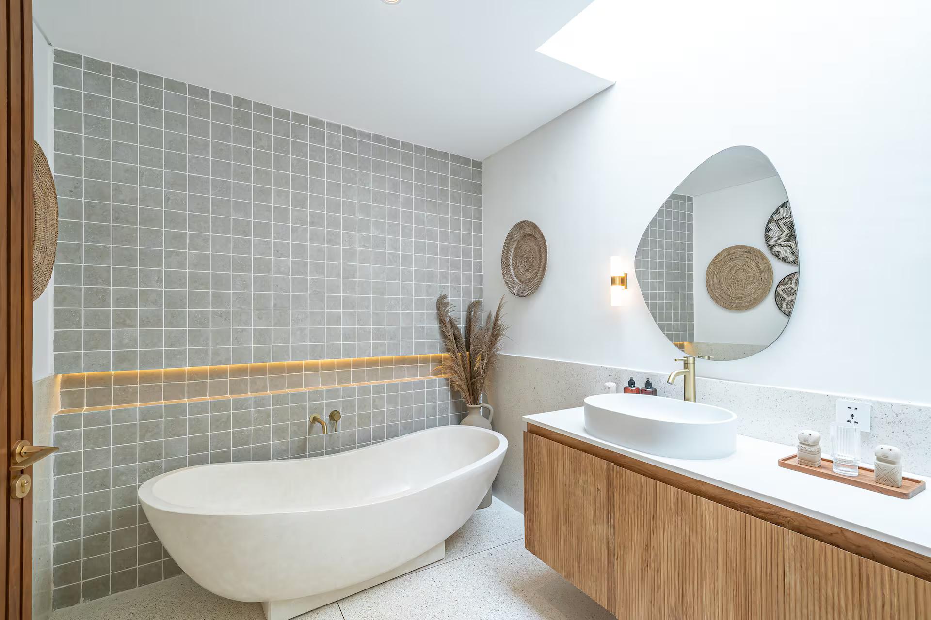 Freestanding tub beside a fluted timber vanity in a bathroom of sage-green tile