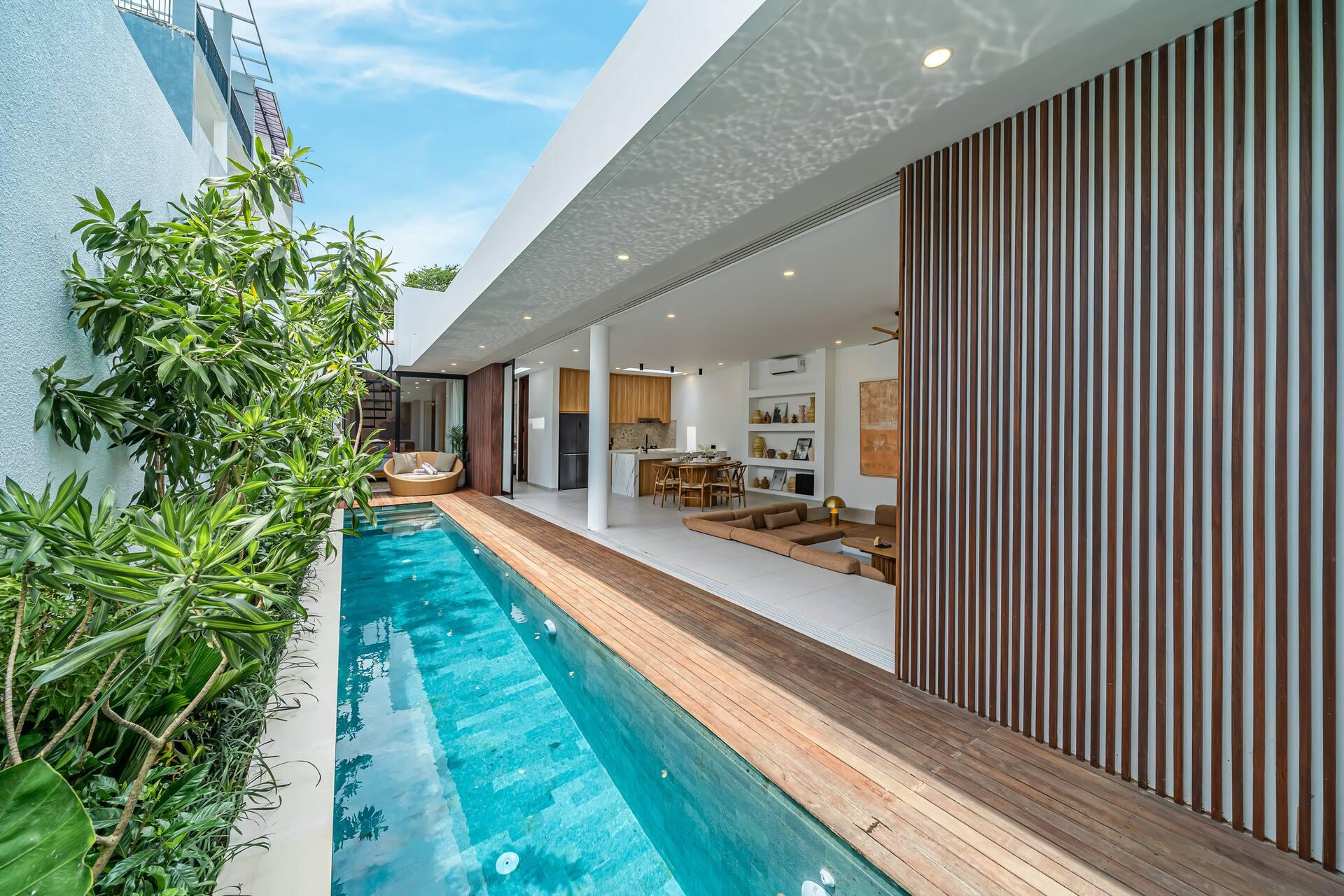 Second lap pool seen along a vertical timber slat screen, the living room opening off the deck