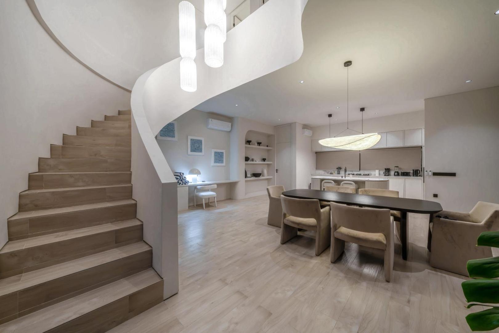 The curved plaster staircase standing free in the middle of the dining room