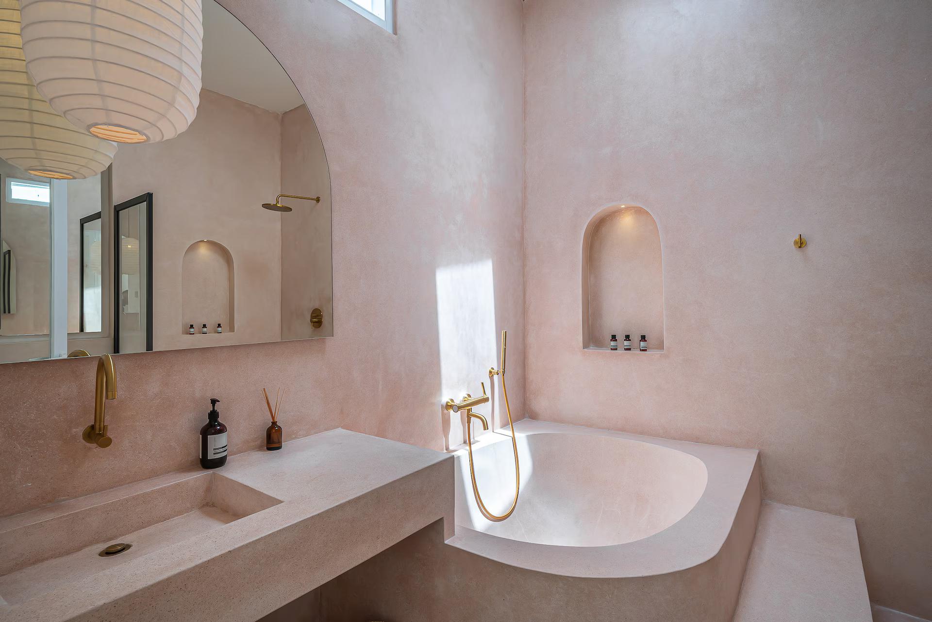 Blush tadelakt bathroom at Villa Halo, plaster curving up into a built-in bath