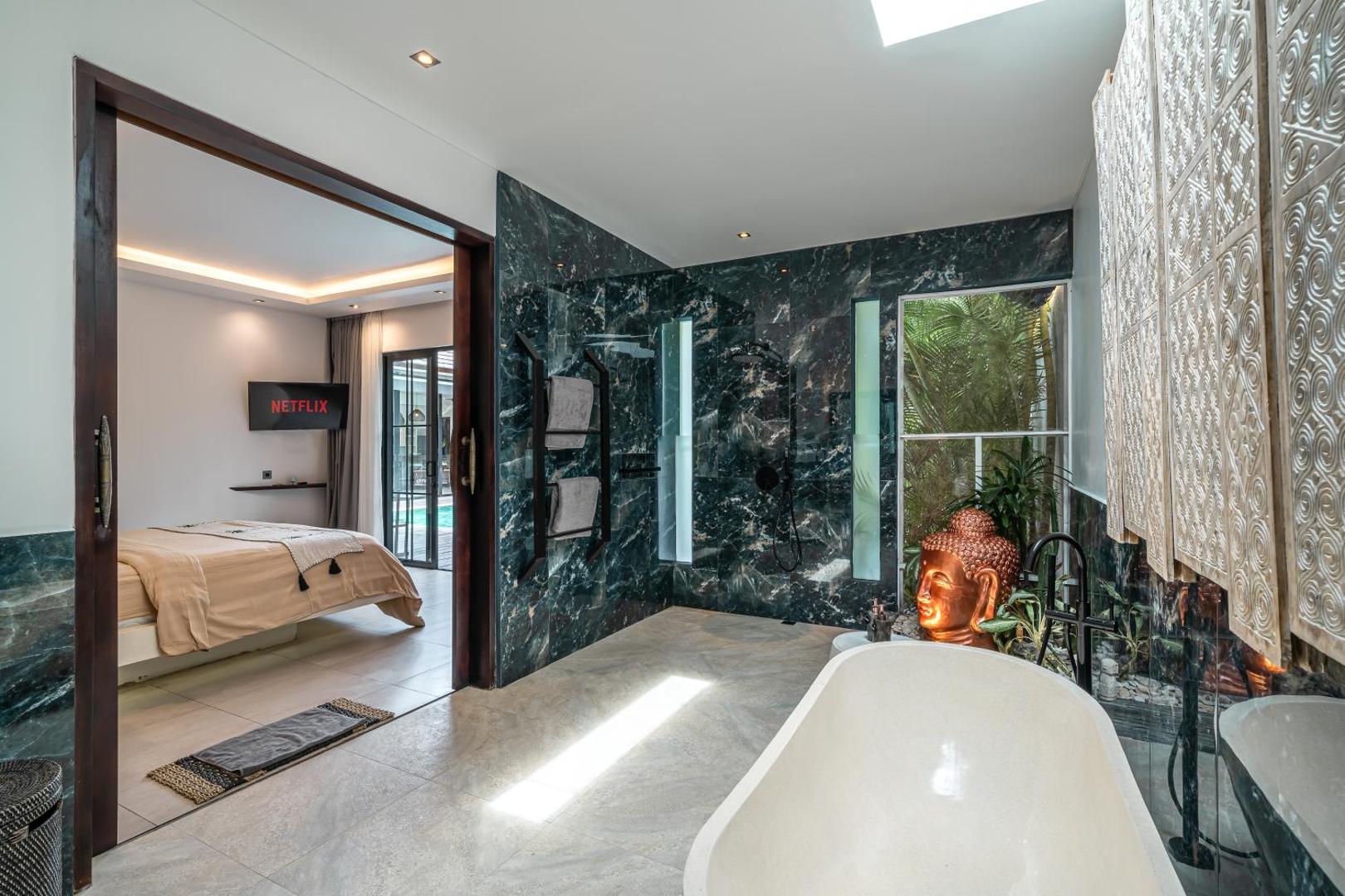 Green-veined marble en-suite with a freestanding tub, open through to the bedroom
