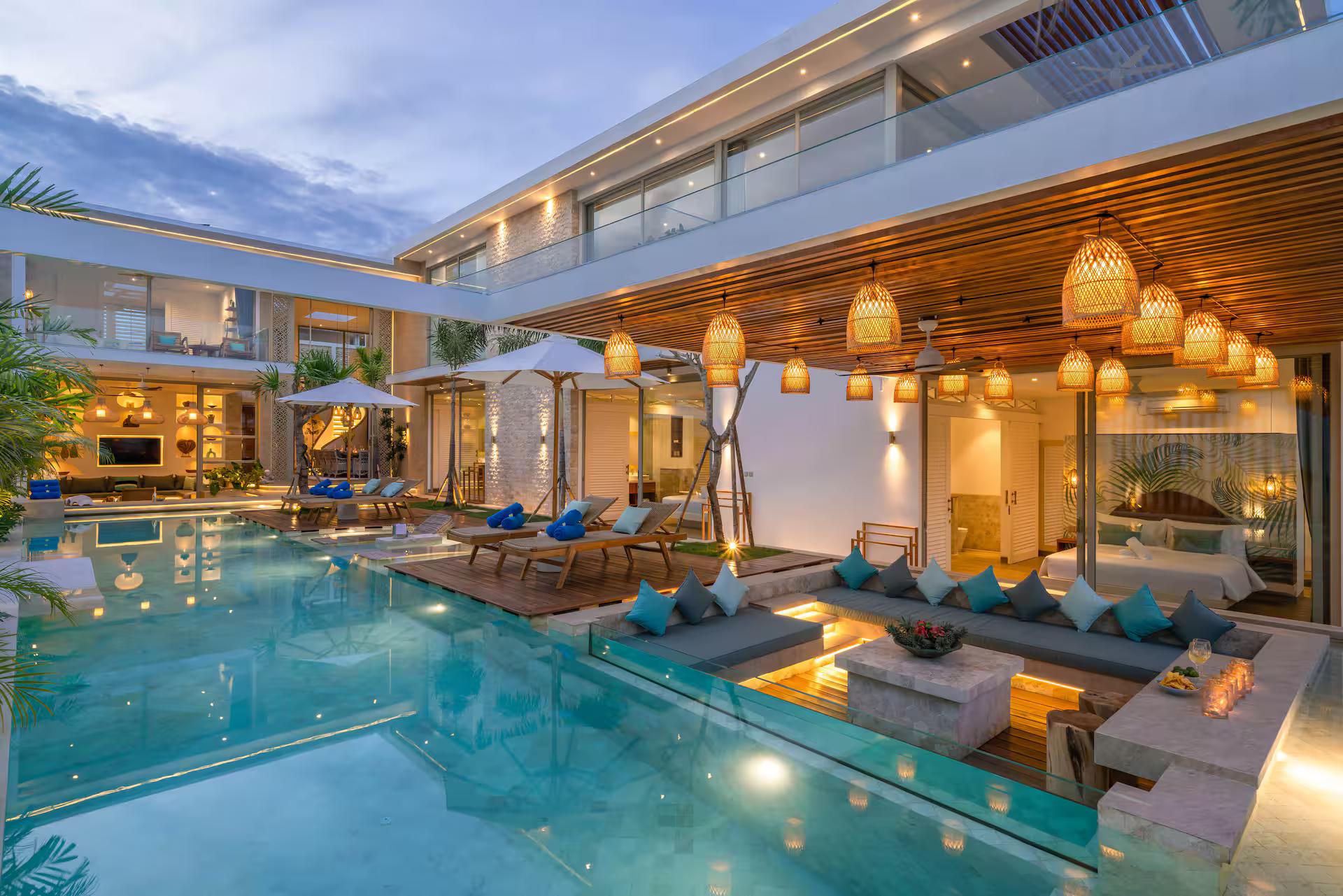 Villa Vola at dusk, the pool lit and rattan pendants glowing along the terrace