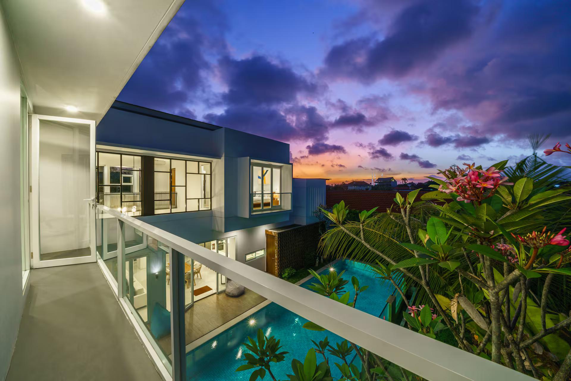 Dusk over the pool seen from the upper walkway, frangipani in flower against the sky