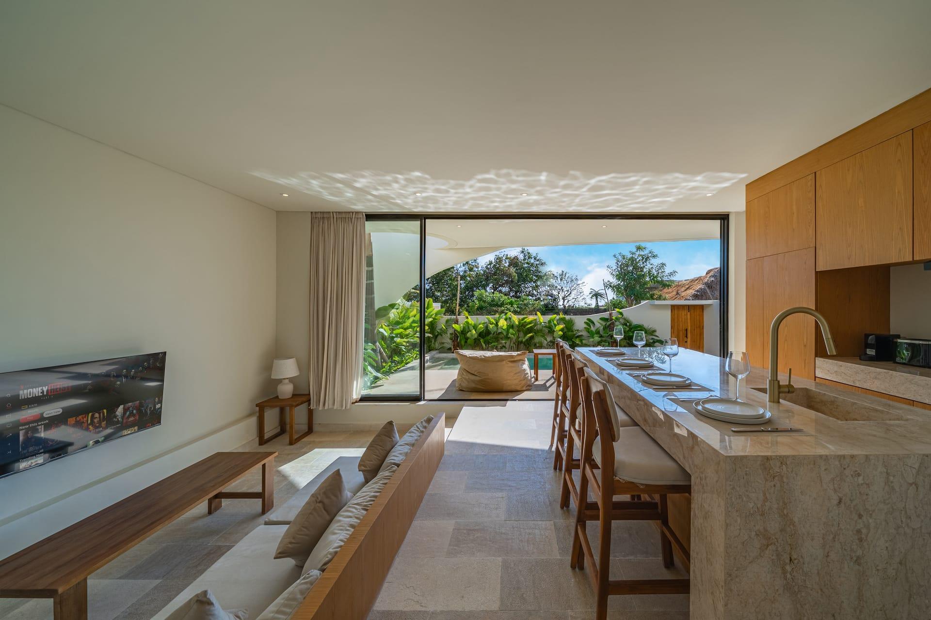 Open-plan living and kitchen at Villa Amber under a vaulted white ceiling, glazed to the garden