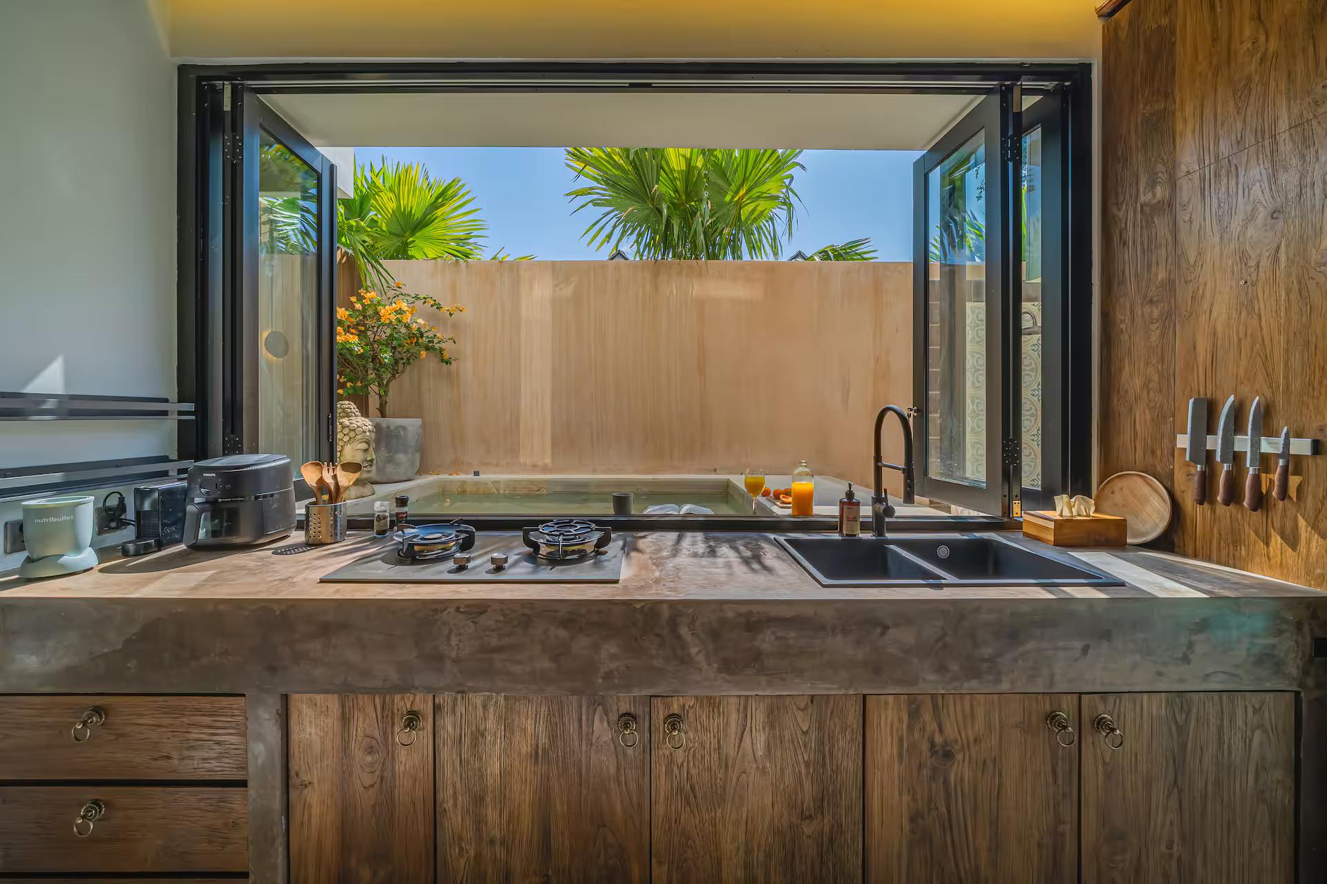 The outdoor kitchen at The Banyan Pererenan, concrete counter and hob open to the pool