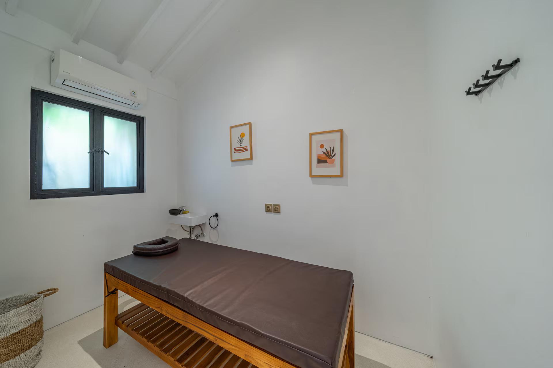 The villa's own spa room, a timber treatment table set against a plain white wall