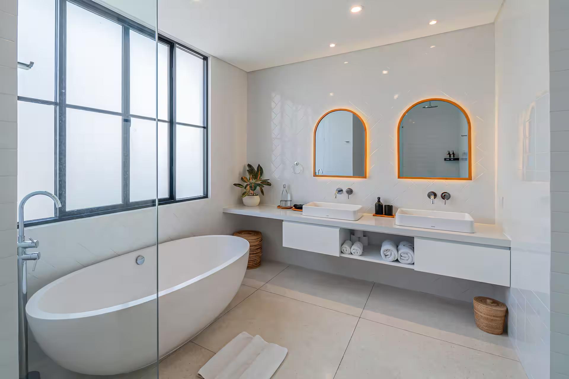 Freestanding oval tub and twin arched mirrors over a double vanity in the master en-suite